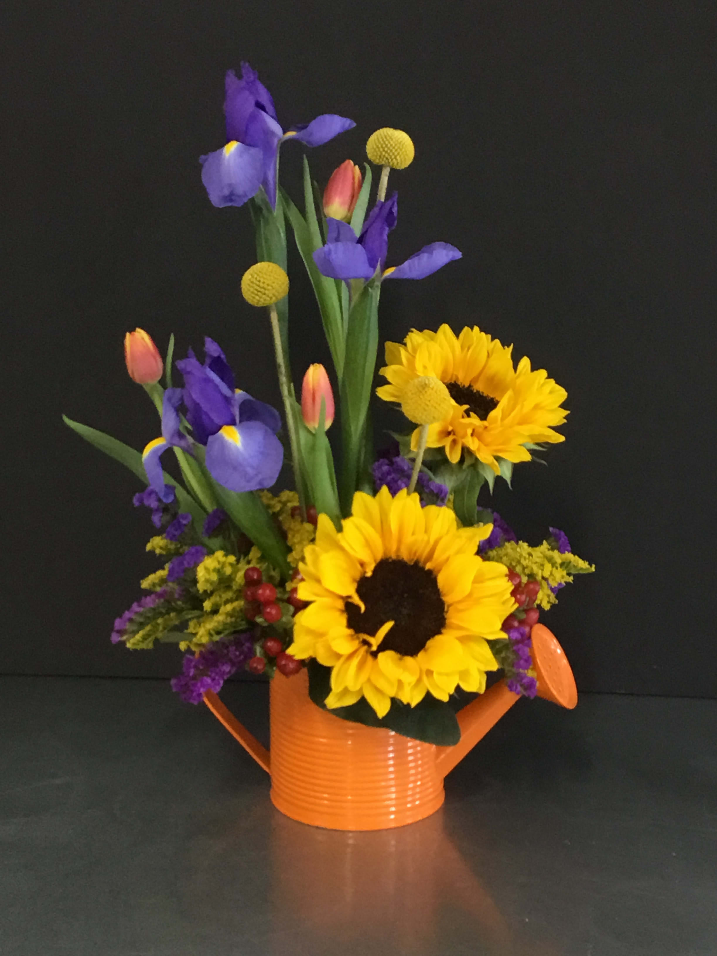 Sunflowers and purple irises arranged in an orange watering can
