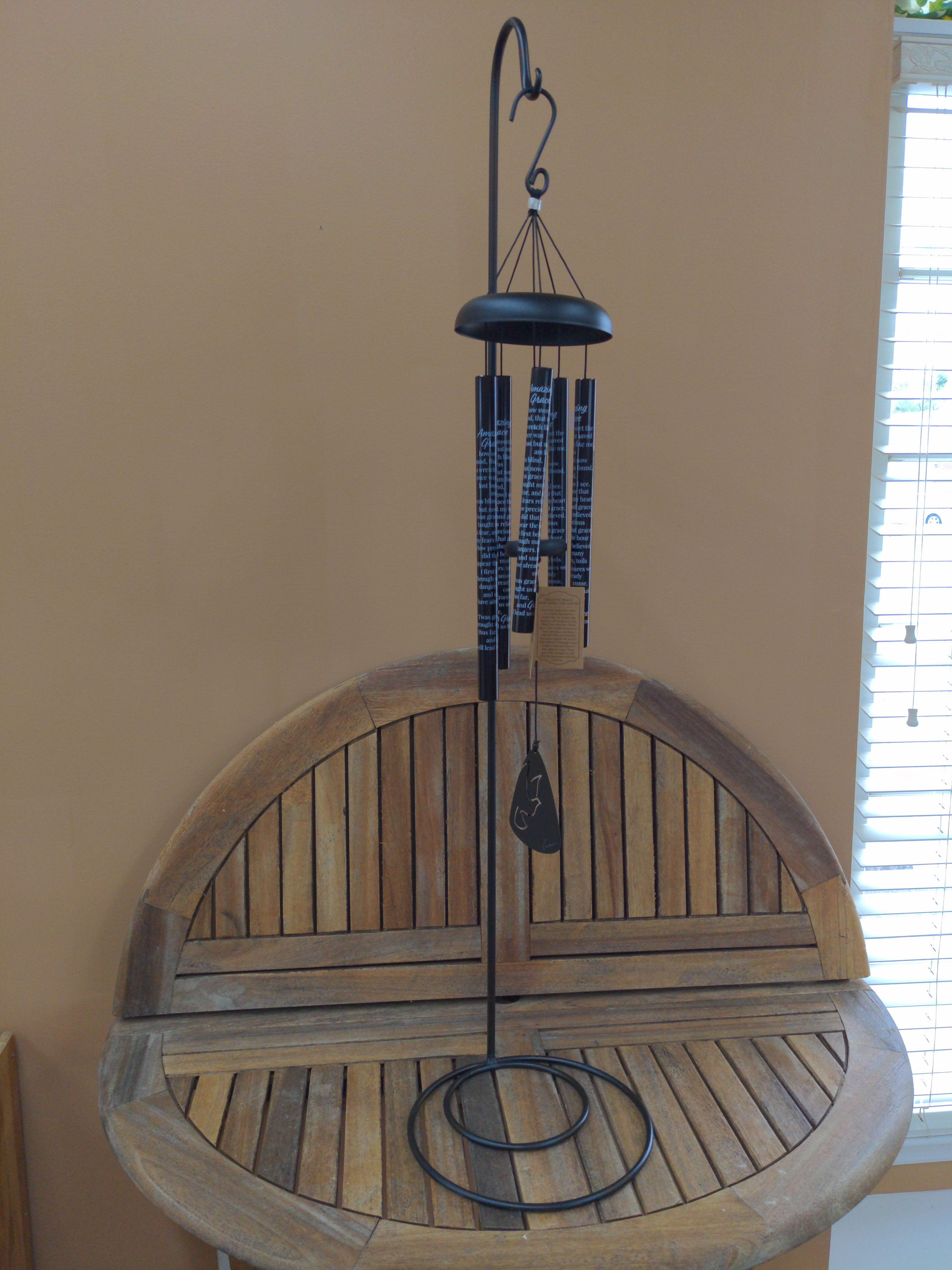 Black metal wind chime hanging above a wooden bench