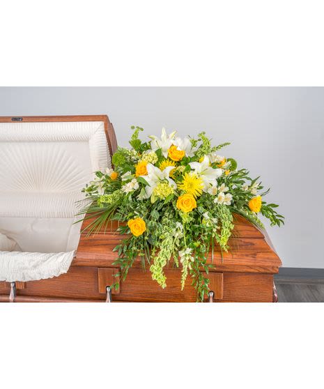 Radiant Gates Casket Spray - A vibrant yet dignified arrangement designed to celebrate a life filled with warmth and light, as its sunny palette is specifically chosen to offer a sense of hope and joy.