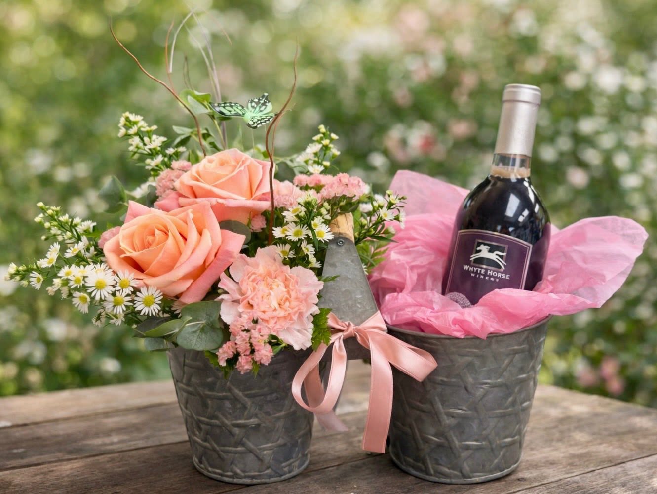 Double Sided Floral Container  -  Mother’s Day Gift Idea She’ll Love!   Looking for something unique this Mother’s Day? Our double-sided container is the perfect gift! One side features a beautiful fresh floral arrangement, while the other is designed to hold a bottle of Mom’s favorite wine—making it a thoughtful and customizable surprise.   Add your own personal touch with her favorite bottle! Please note: We provide the container and flowers only. Wine is not included or sold by us. Flowers will vary. Call if you have specific requests.