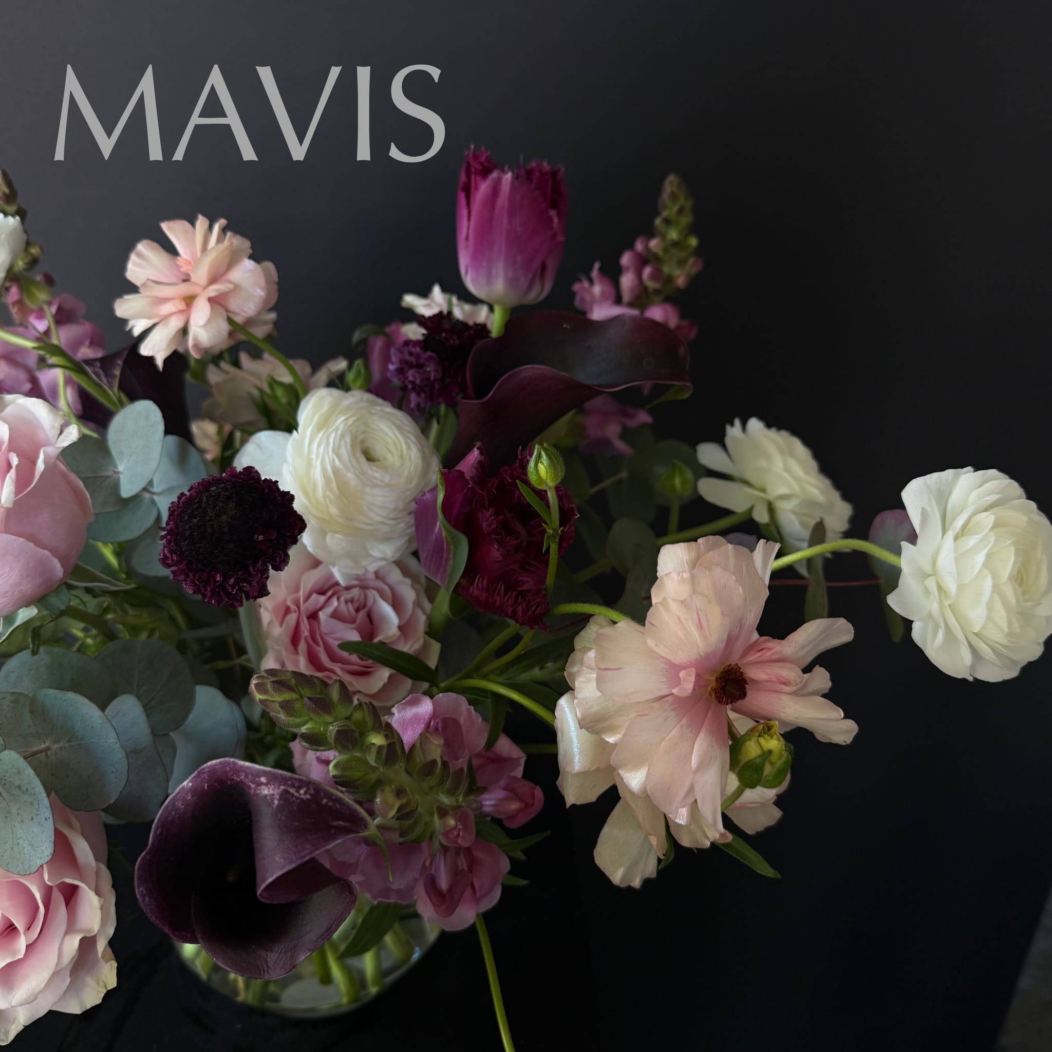 Mixed bouquet with pink, white, and deep purple flowers in a glass vase