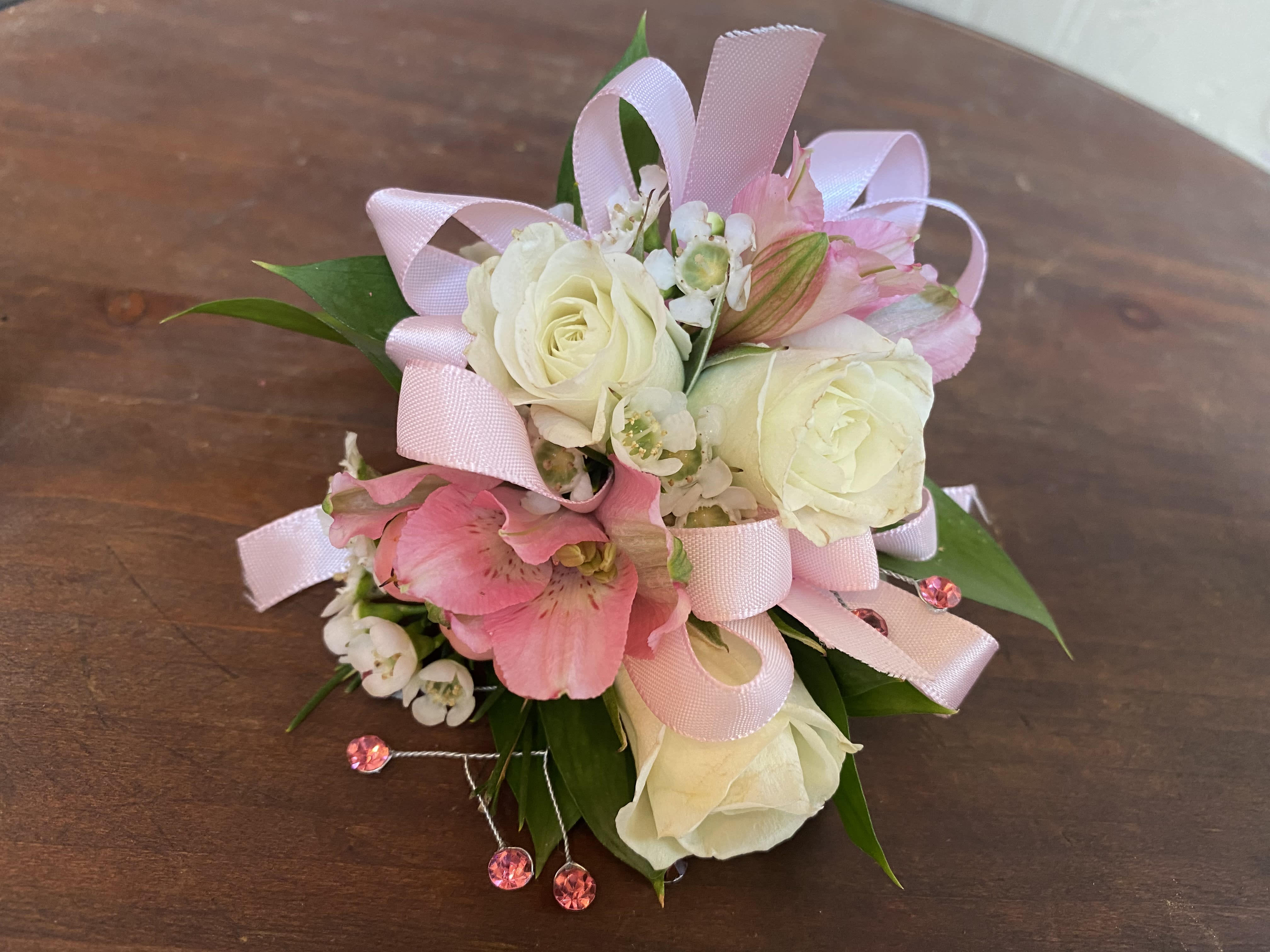 Small pink and white floral corsage with ribbon loops