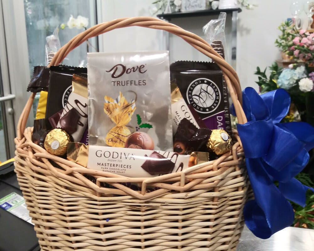 Wicker basket filled with assorted chocolates and a blue ribbon bow