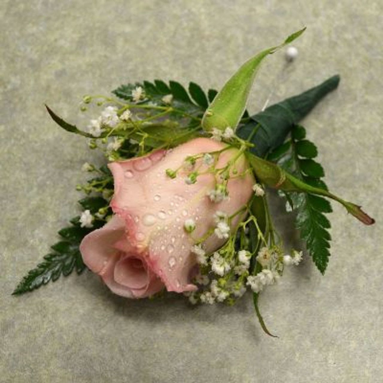 Pink calla lily corsage with small white flowers and greenery