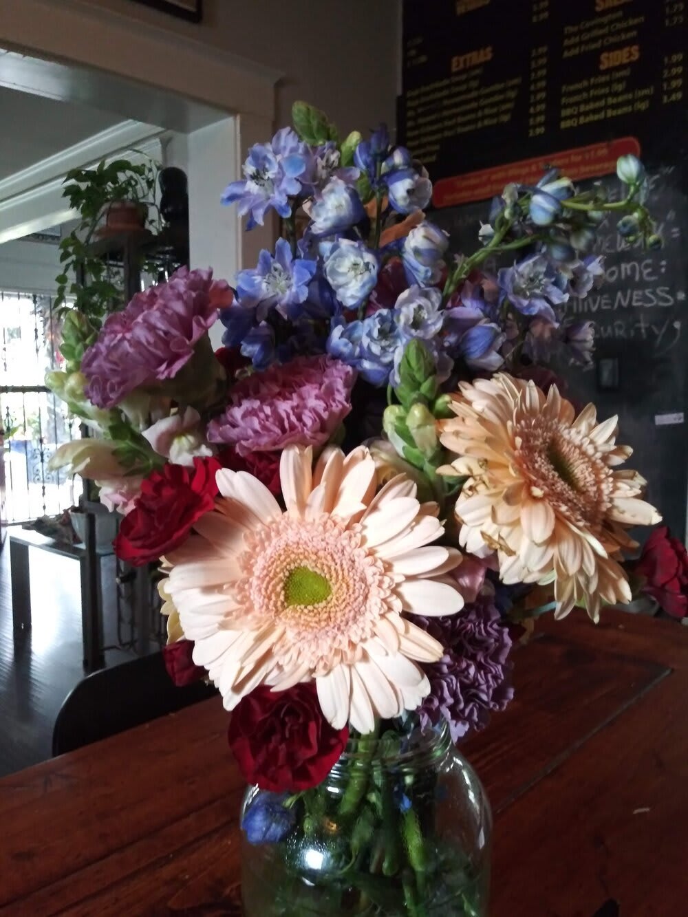 Mixed bouquet with gerbera daisies and blue-purple flowers in a glass vase