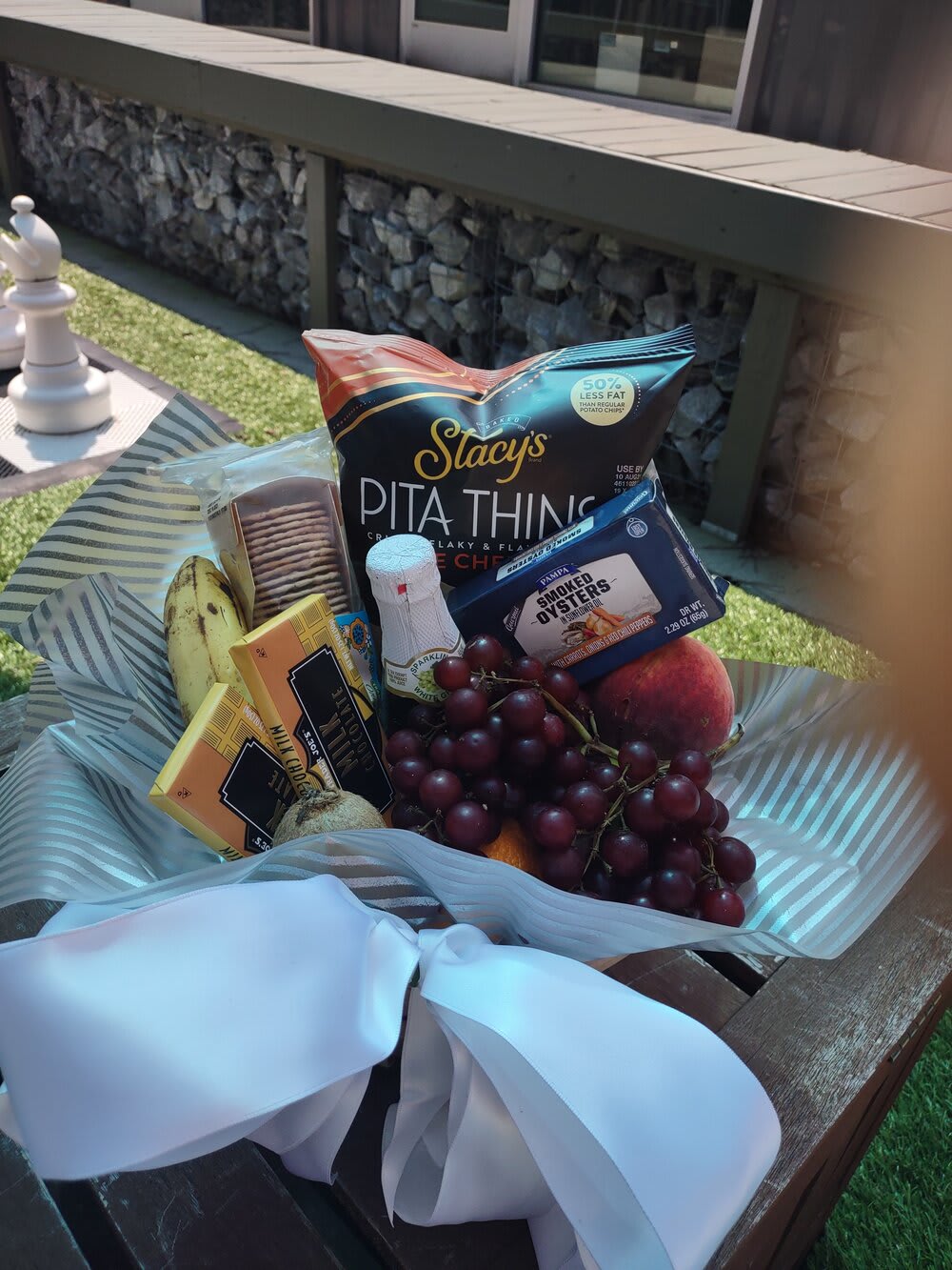 Gift basket with snacks, fruit, and a white ribbon