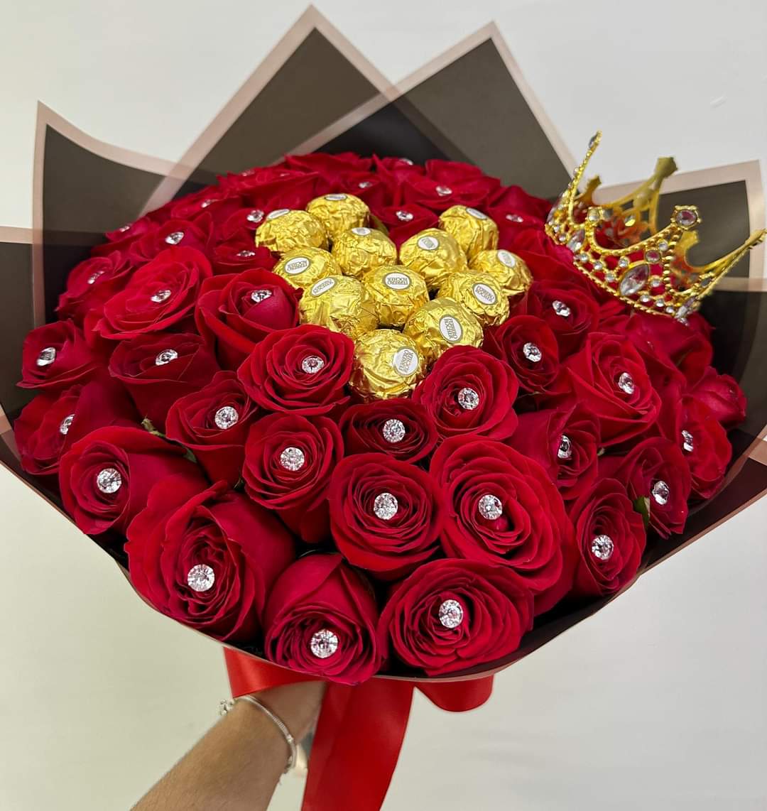 Bouquet of red roses with gold-wrapped chocolates and a jeweled crown