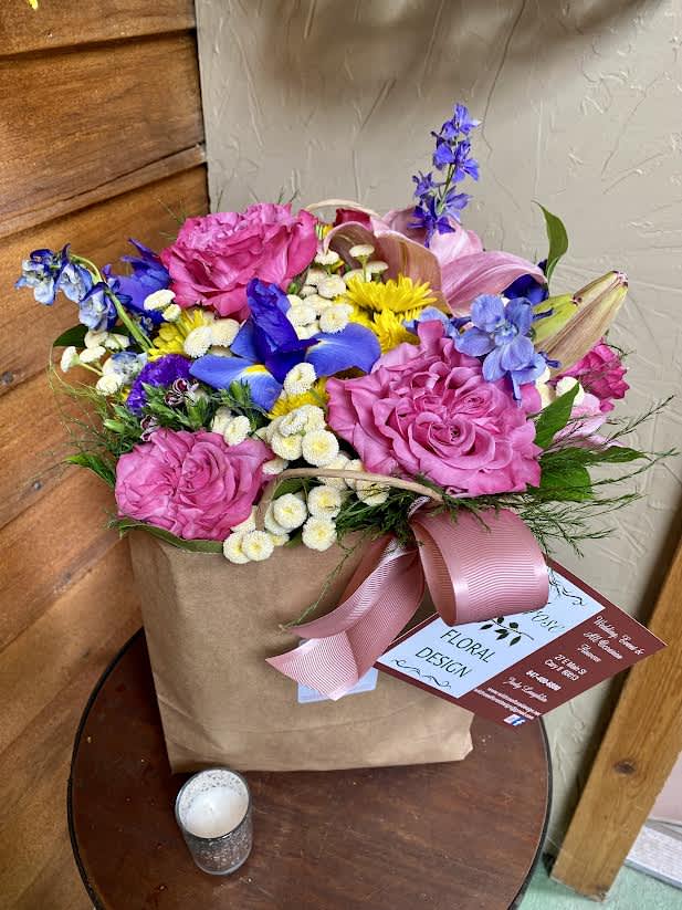 Mixed bouquet in a kraft paper bag with pink ribbon