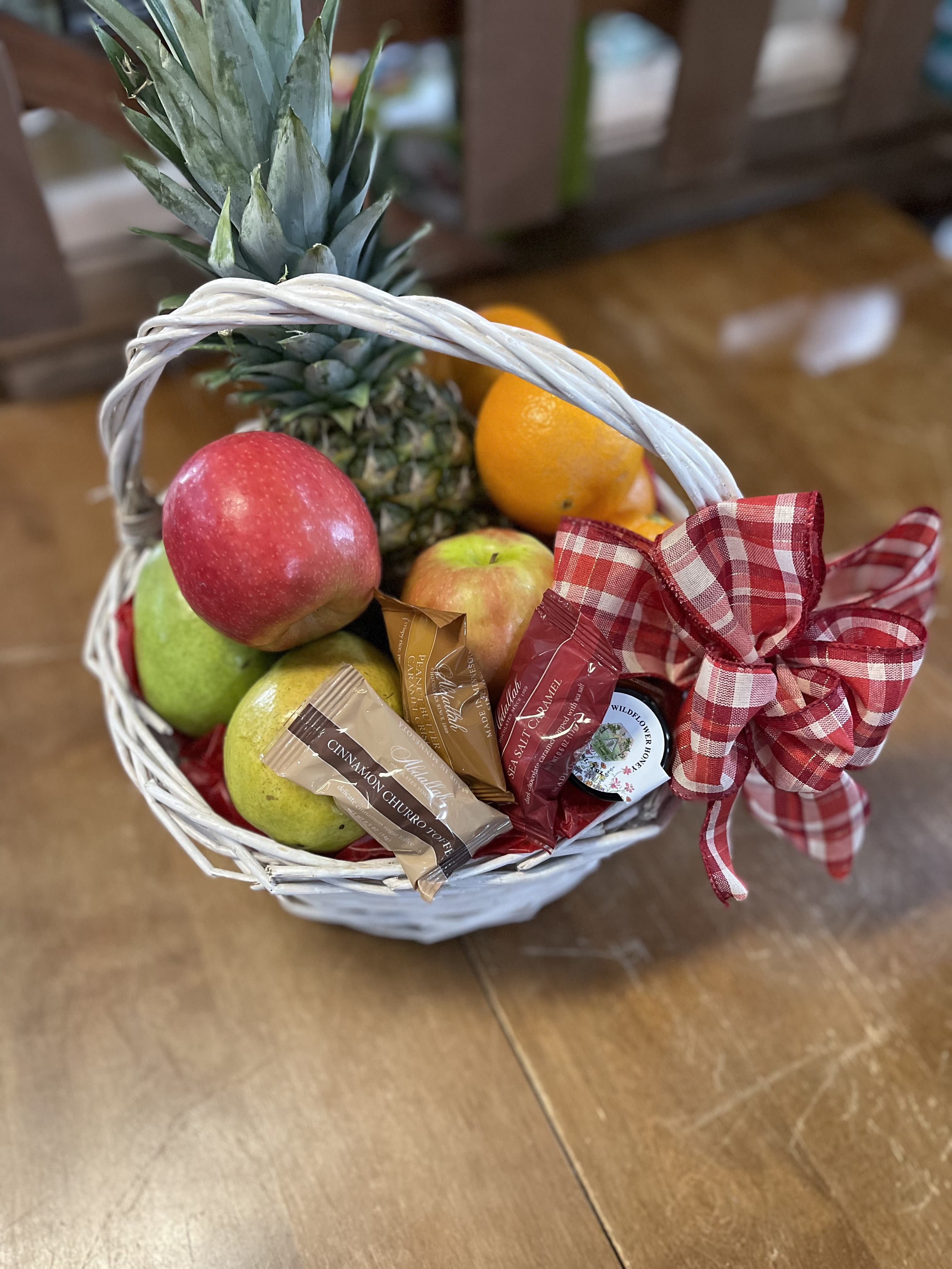 Fruit basket with pineapple, apples, oranges, and wrapped candies