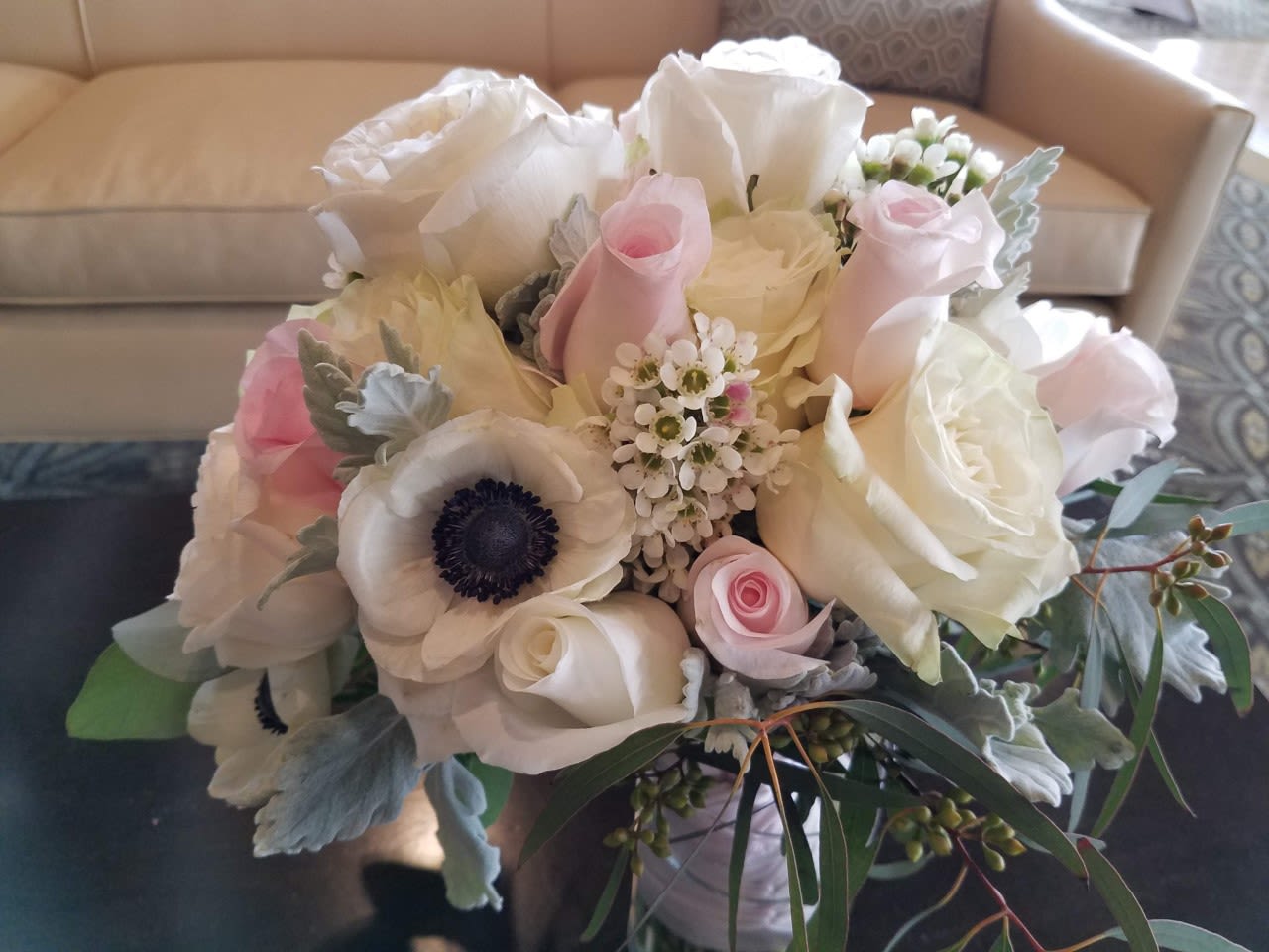 Round arrangement of white and pale pink roses with white anemones in a low vase