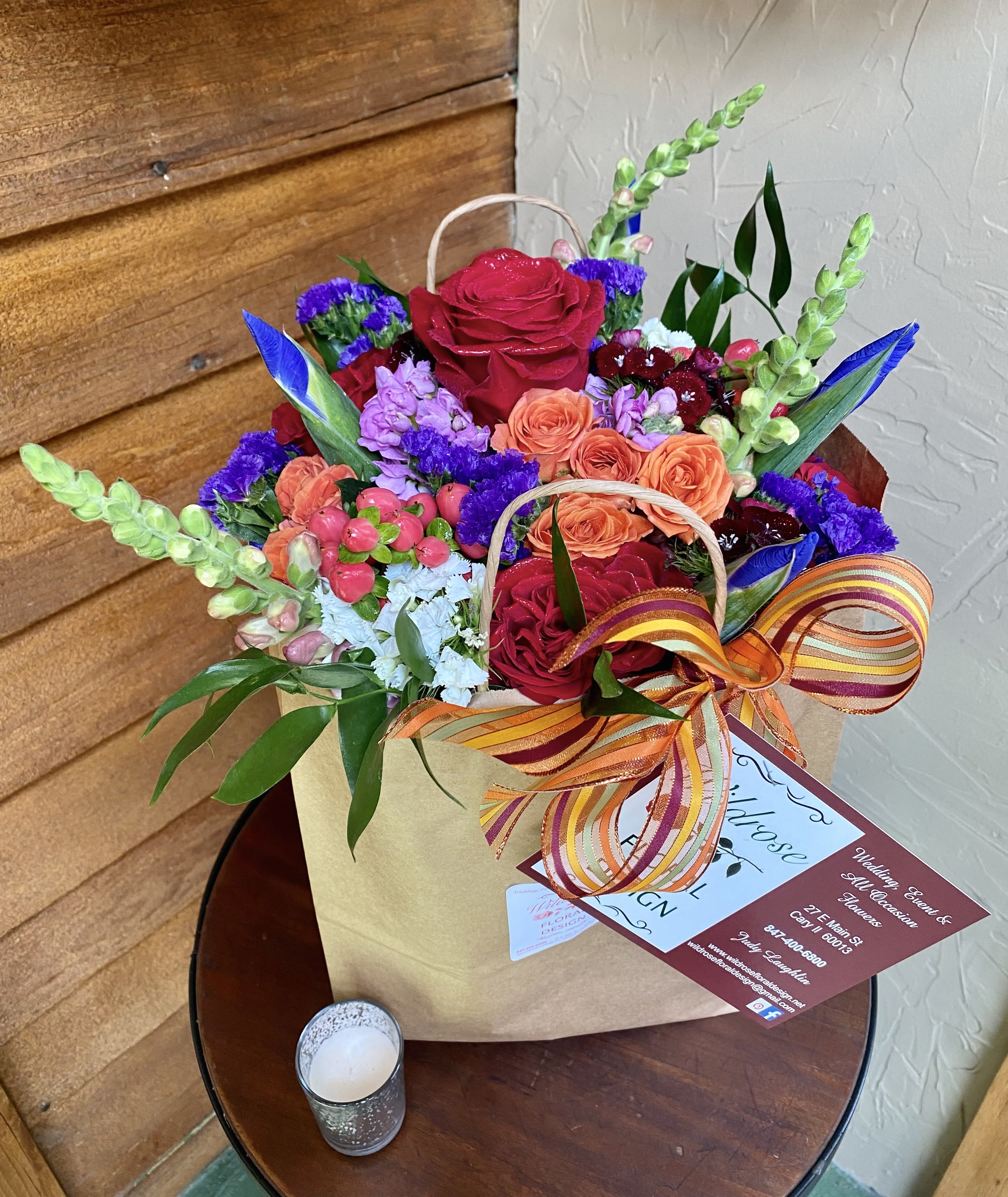 Mixed bouquet of red, orange, purple, and blue flowers in a gift bag