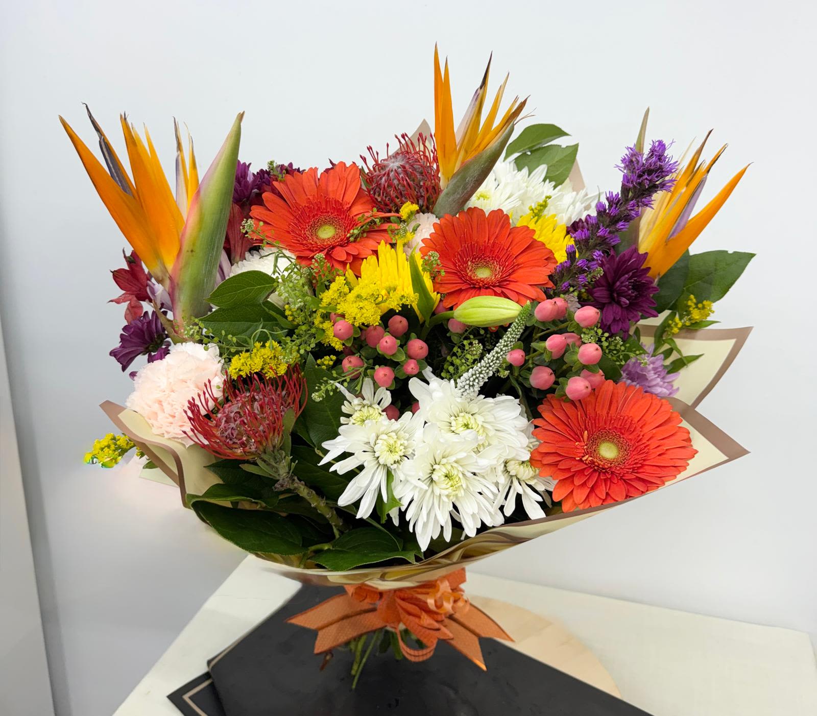 Tropical Sunset Bouquet - Our Tropical sunset Bouquet is What better choice of flowers than this hand-tied bouquet in elegant shades of orange and gold featuring Gerbera, Veronica, Hypericum ,differents moms and eye-catching Strelitzia also known as Bird of Paradise Flower