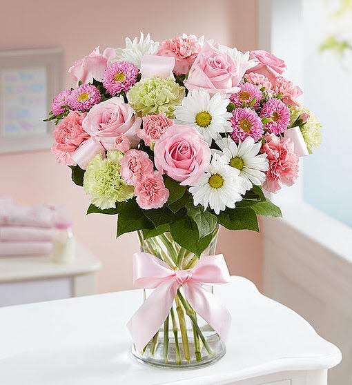 Pink and white mixed bouquet in a glass vase with a pink ribbon