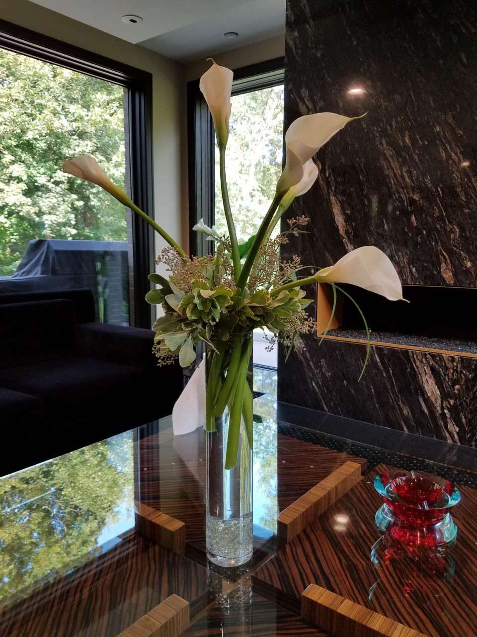 White Elegance - The Pure, Simple Elegance of a Calla Lilly Bouquet Will Be the Star of Any Room It is Placed in. Five Perfect Callas Arranged With Lush Foliage and Wispy Grasses is Designed in a Glass Cylinder.