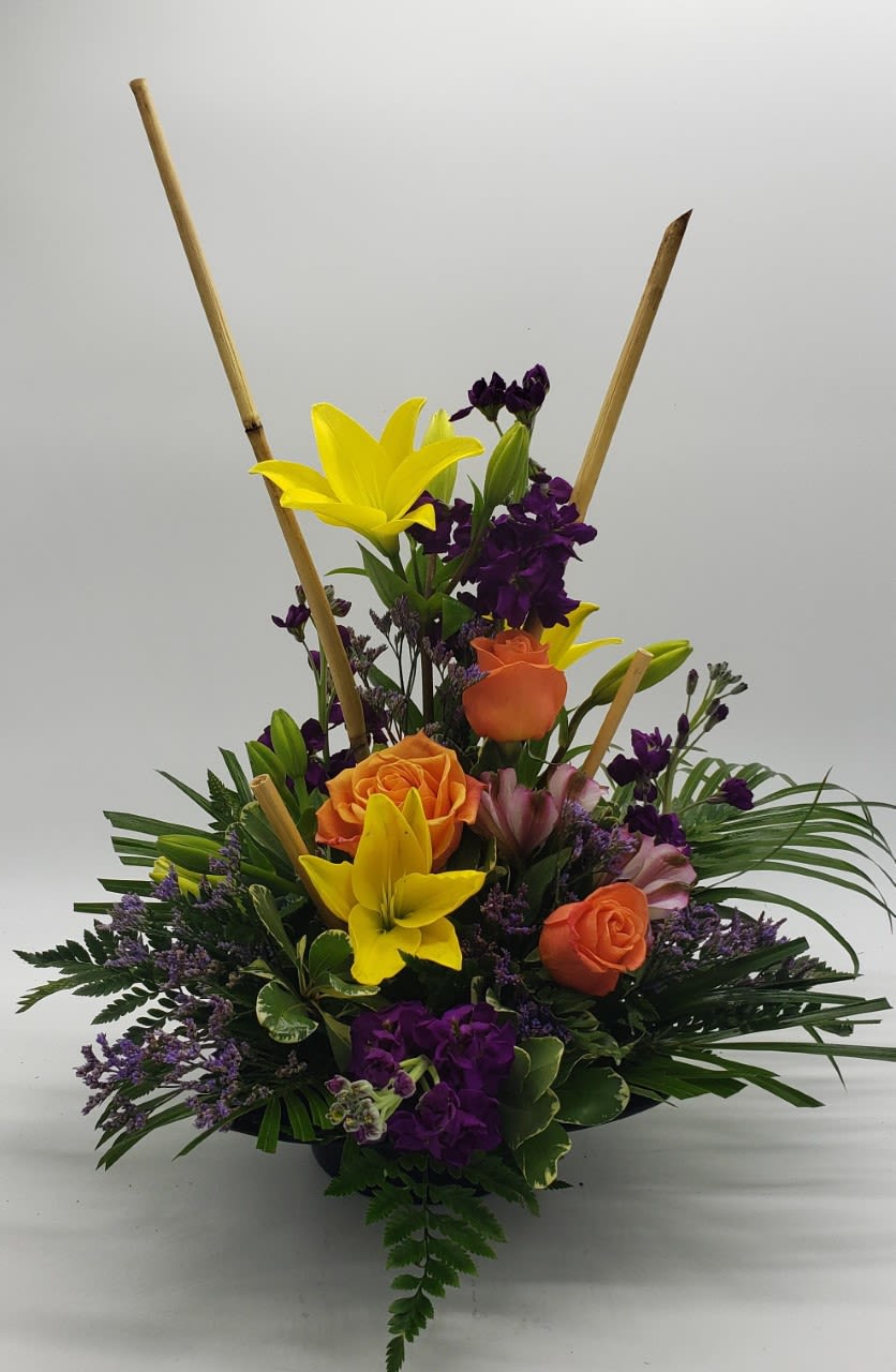 Upright bouquet with yellow lilies, orange roses, and purple flowers