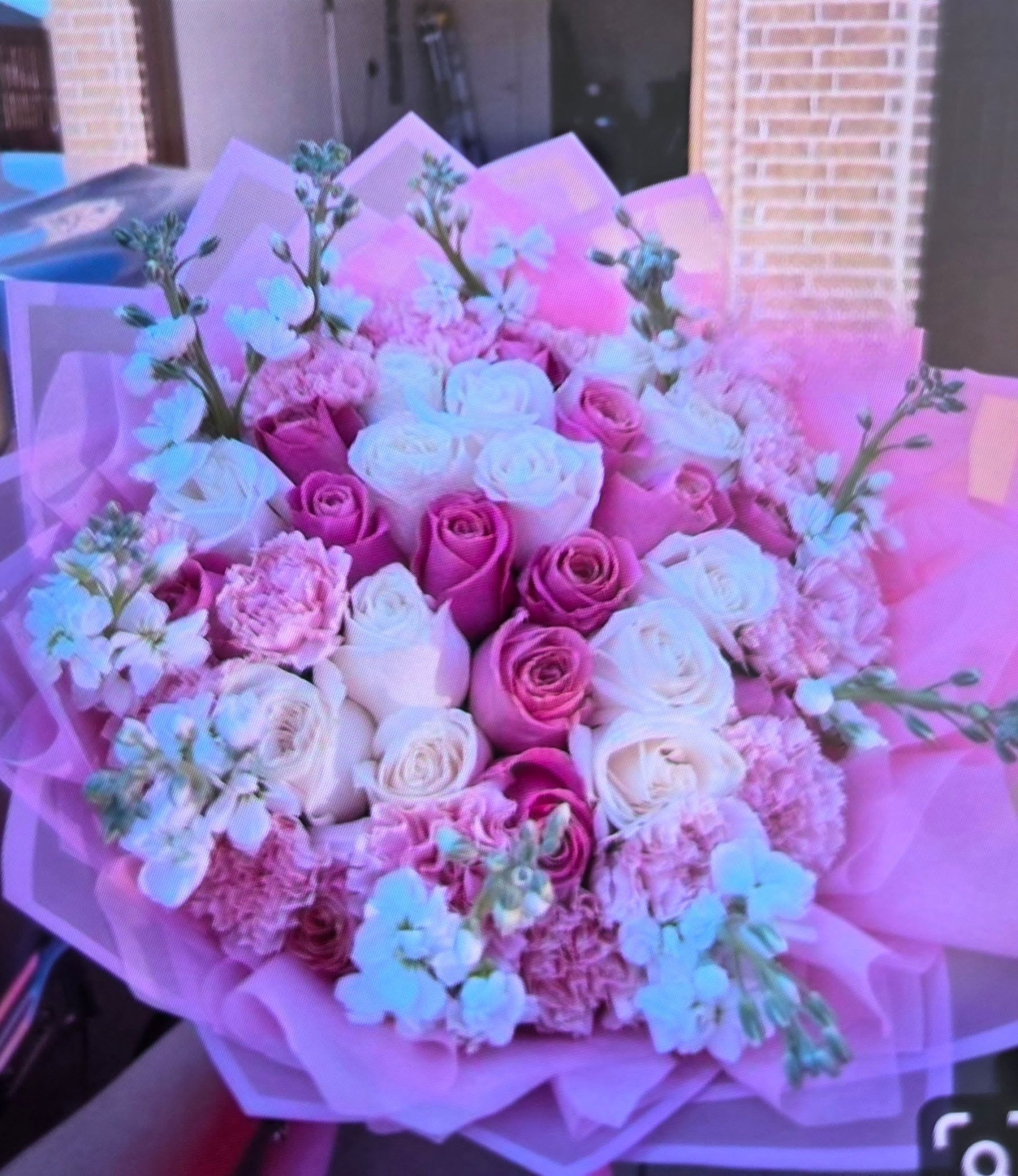 Pinky Promise Pink Rose Bouquet - 2 Dozen Roses - A lush, rounded bouquet of pink and white roses designed to make the person you're thinking of feel cherished - ideal as a birthday bouquet, anniversary flowers, or a Valentine's Day surprise. The Pinky Promise pink rose bouquet pairs two dozen roses with clusters of pink carnations and small pale blue filler blooms for a soft, romantic look that reads feminine and celebratory.  The arrangement is tightly gathered for a full, plush texture and wrapped in layered pink paper that adds a delicate, gift-ready finish. Whites brighten the deeper pinks while the pale blue accents add a whisper of contrast; the mix of roses, carnations, and filler creates both visual depth and gentle scent.  Perfect for saying "I love you," "happy birthday," or "congratulations," this bouquet arrives ready to present and will make the recipient feel truly seen and celebrated. For best display, trim stems and place in fresh water; order early for seasonal occasions to ensure availability.