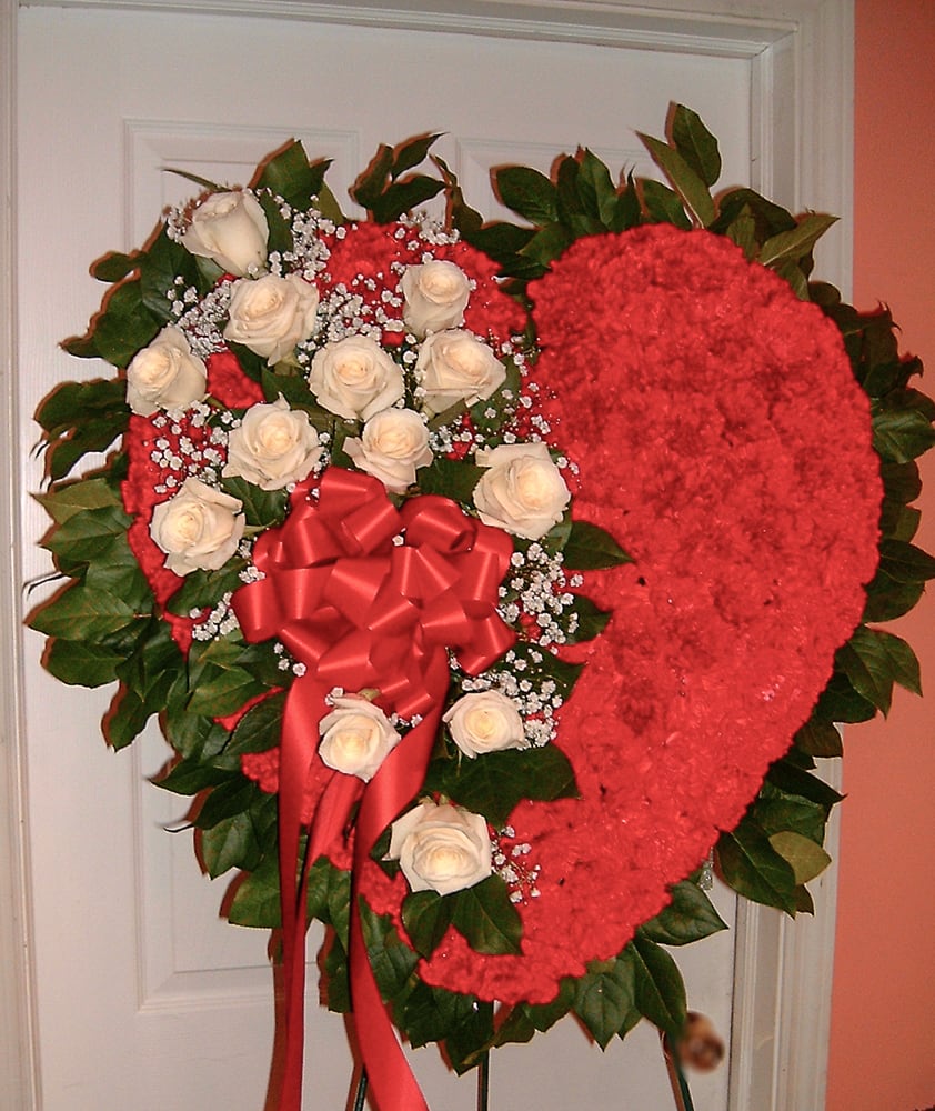 Heart-shaped floral spray with white roses and a red bow