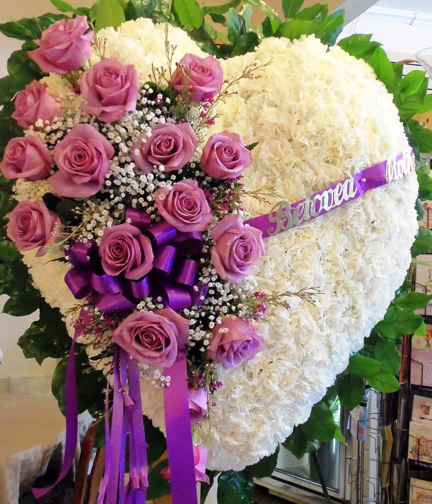 Heart-shaped floral tribute with pink roses and white blooms