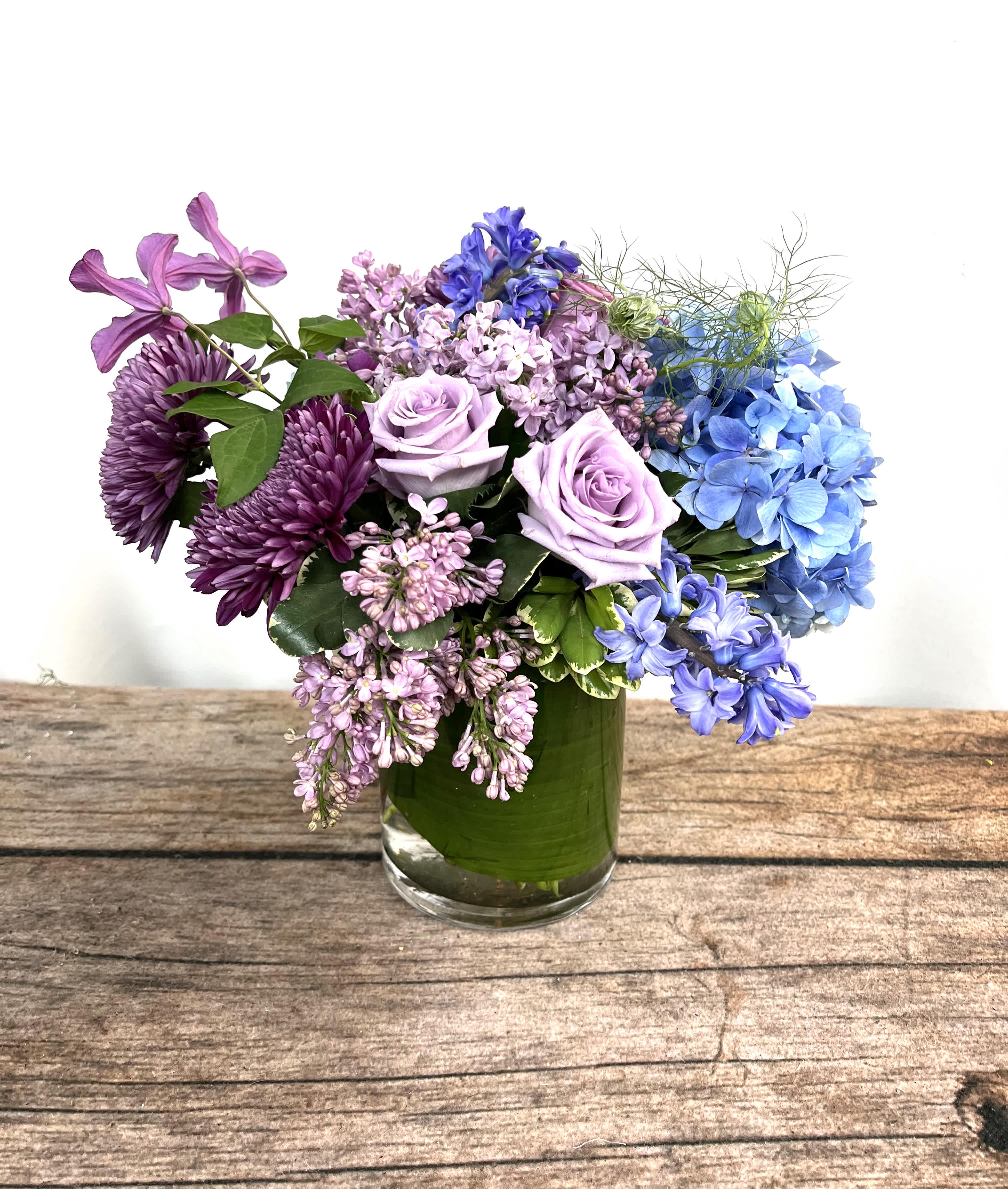 Purple and blue flowers arranged in a glass vase