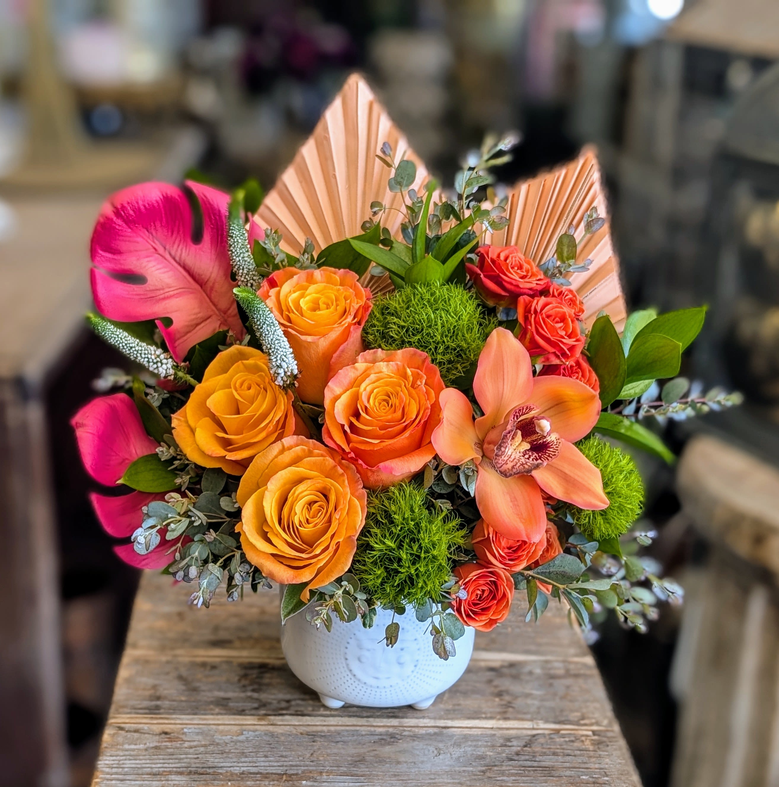 Bright bouquet of orange and pink roses in a white vase