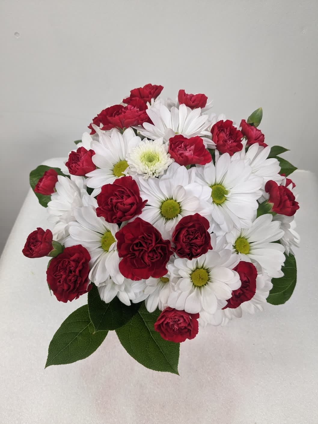 Bouquet of red carnations and white daisies with green centers