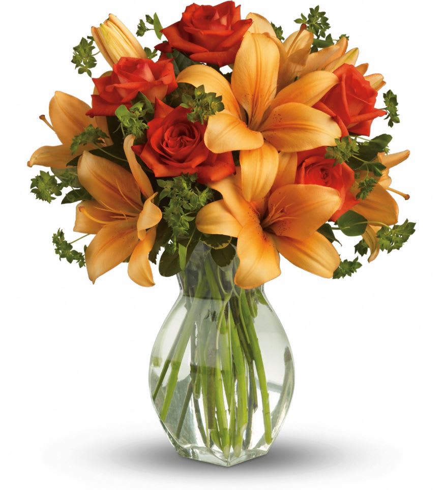 Orange lilies and red roses arranged in a clear glass vase