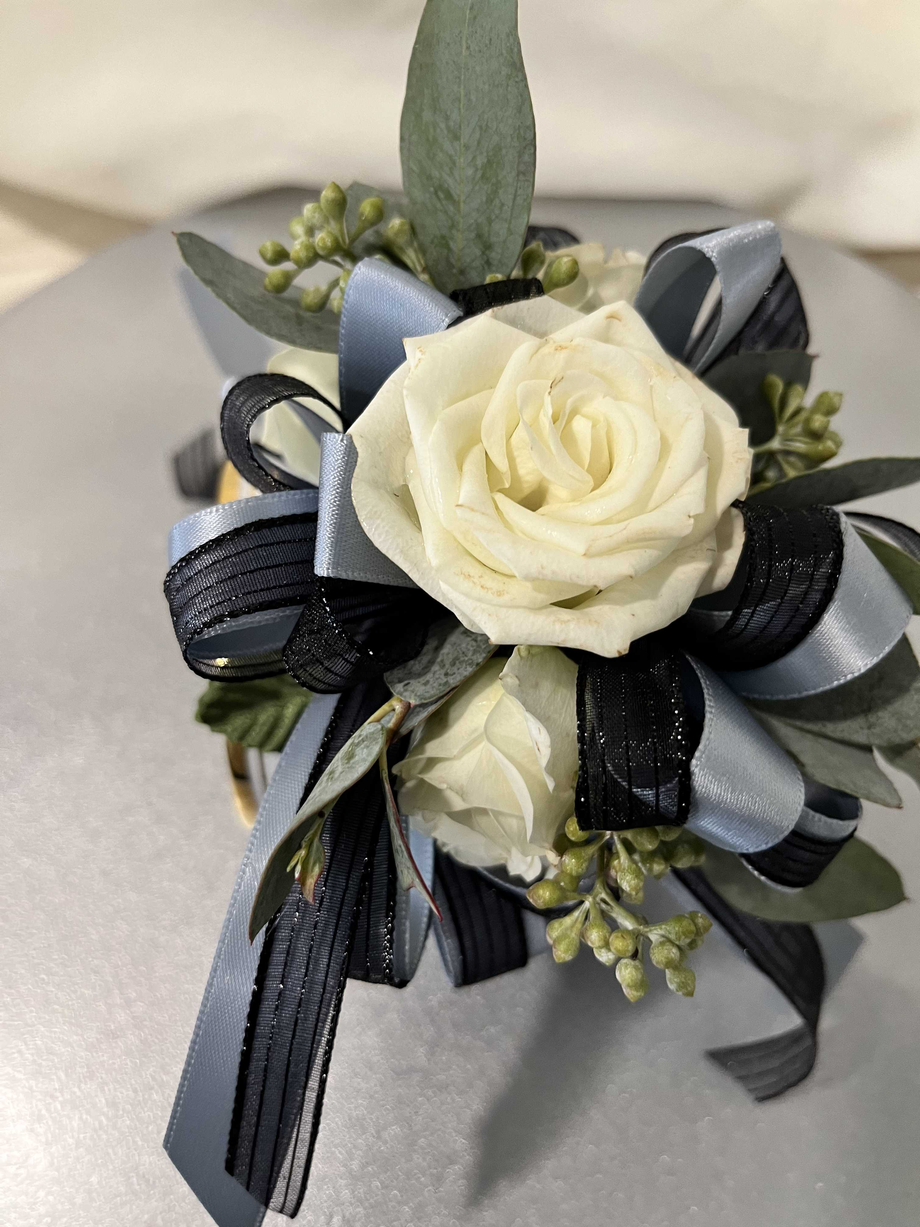 White rose corsage with blue and black ribbon accents