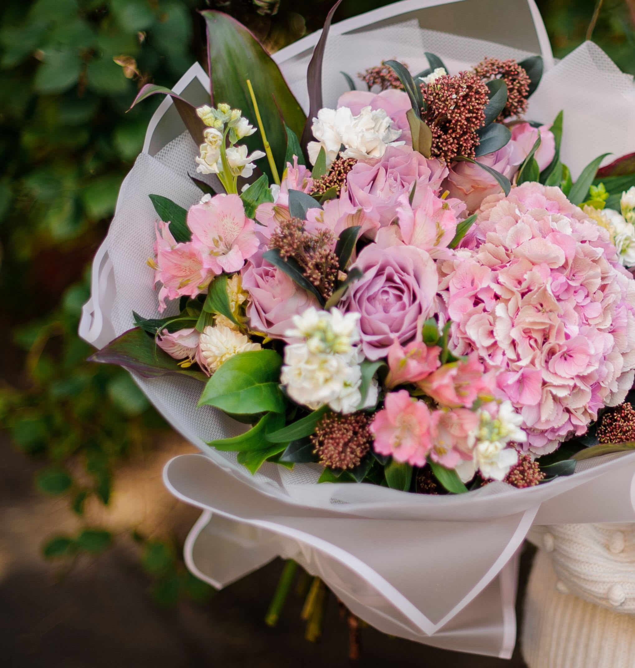 Pink and lavender bouquet with hydrangea and roses wrapped in white paper