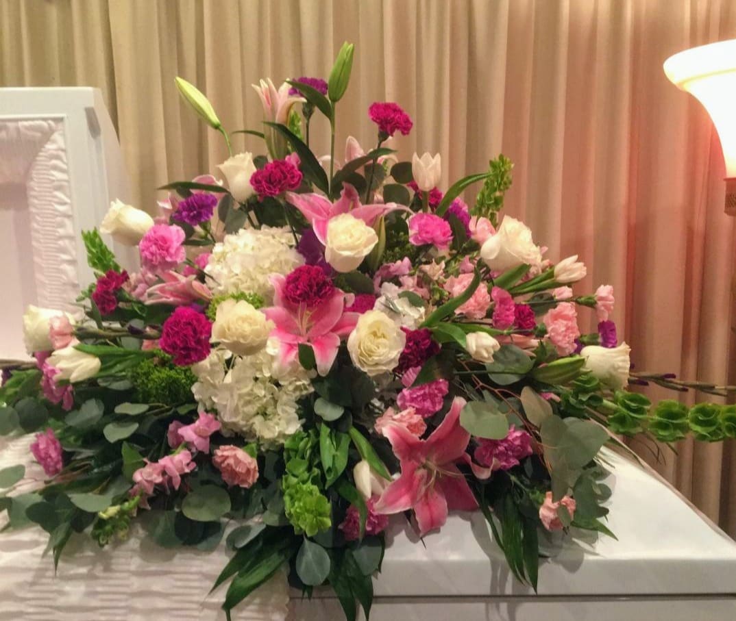  Garden of Memories FRESH Casket Spray - Bring a gentle radiance to the memorial service with this lovely multicolored casket spray of roses, lilies and other favorites. A beautiful way to honor the departed.  The elegant arrangement includes hydrangea, roses, carnations,  lilies, and other fillers and mixed greens.