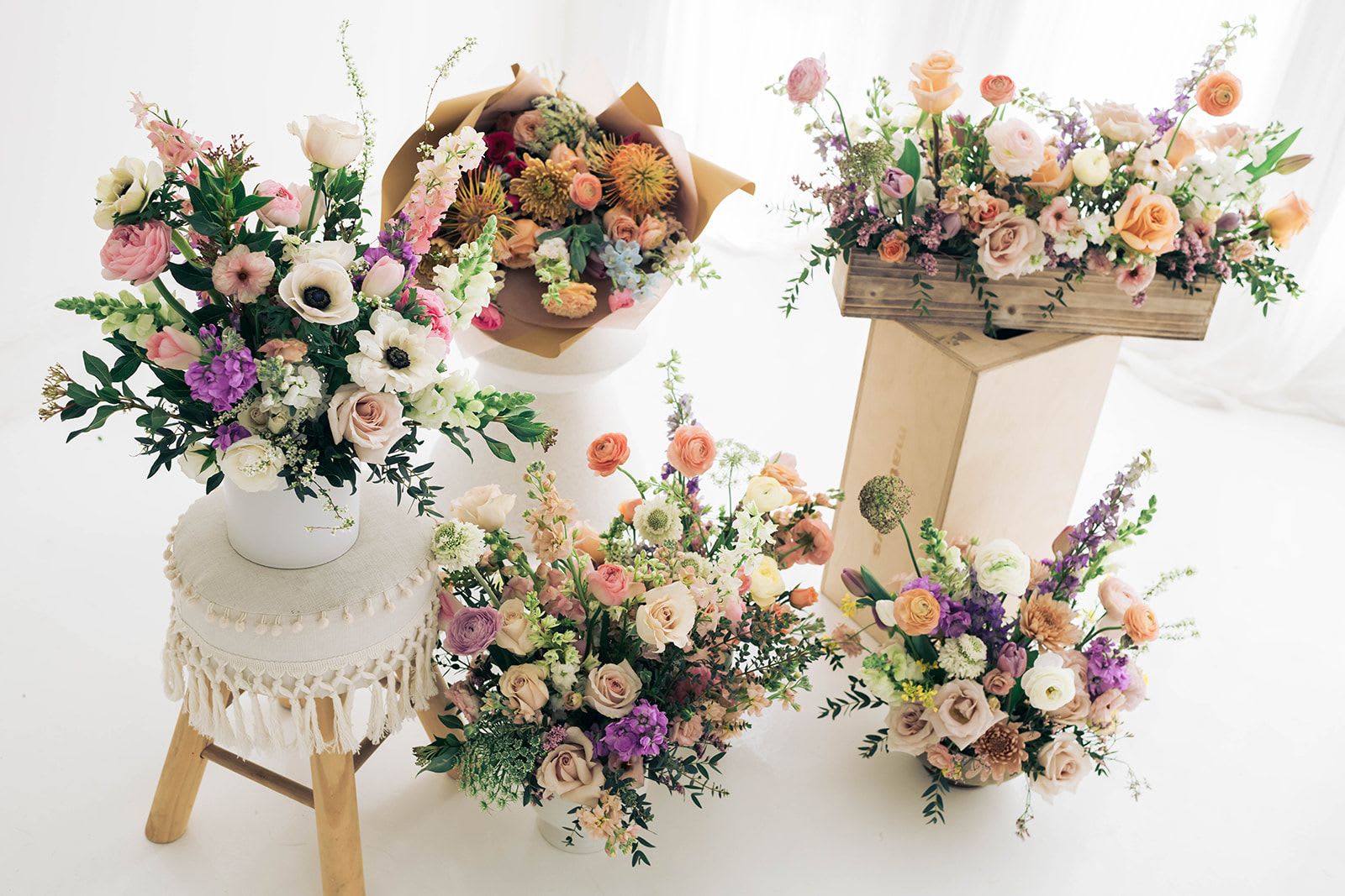 Assorted pastel flower arrangements in vases and boxes