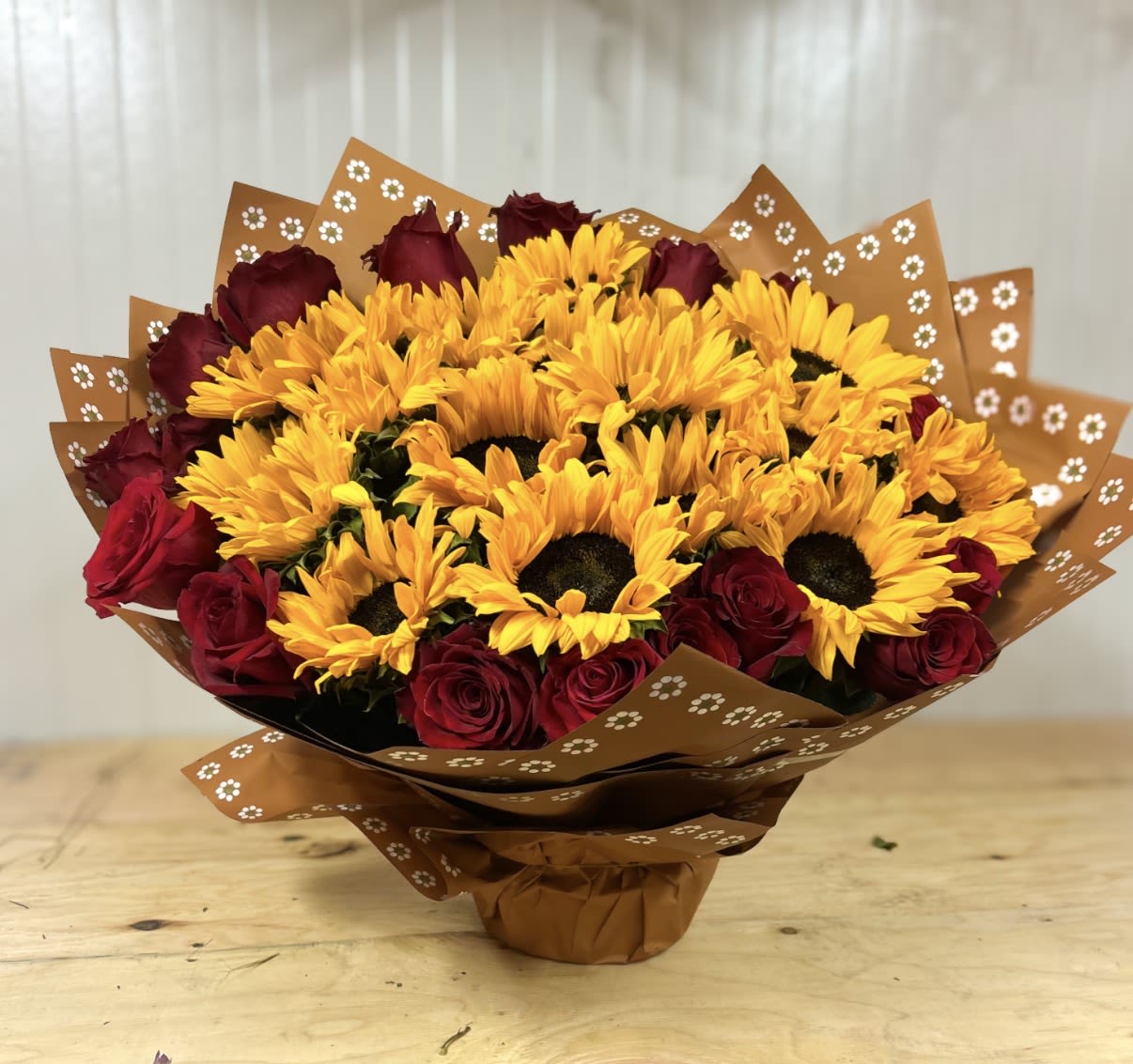 Golden Romance  - A bold and radiant arrangement that captures the warmth of golden hour. This bouquet features vibrant sunflowers at the center, surrounded by rich red roses for a striking contrast of sunshine and romance. 
