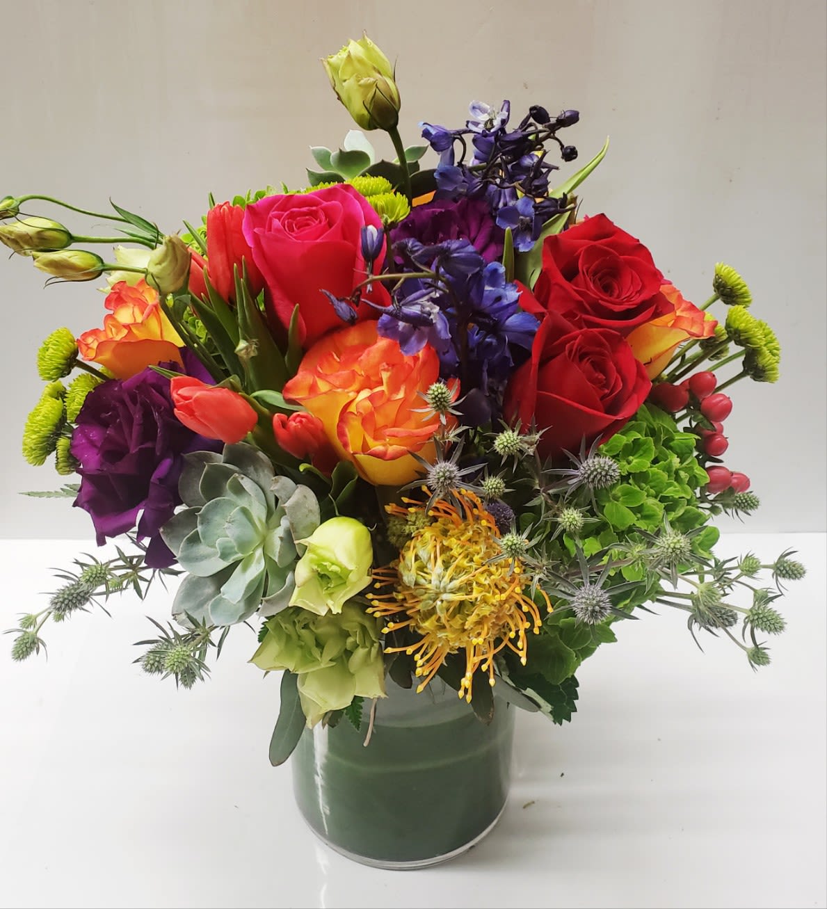 Colorful mixed bouquet in a glass vase with roses and assorted blooms