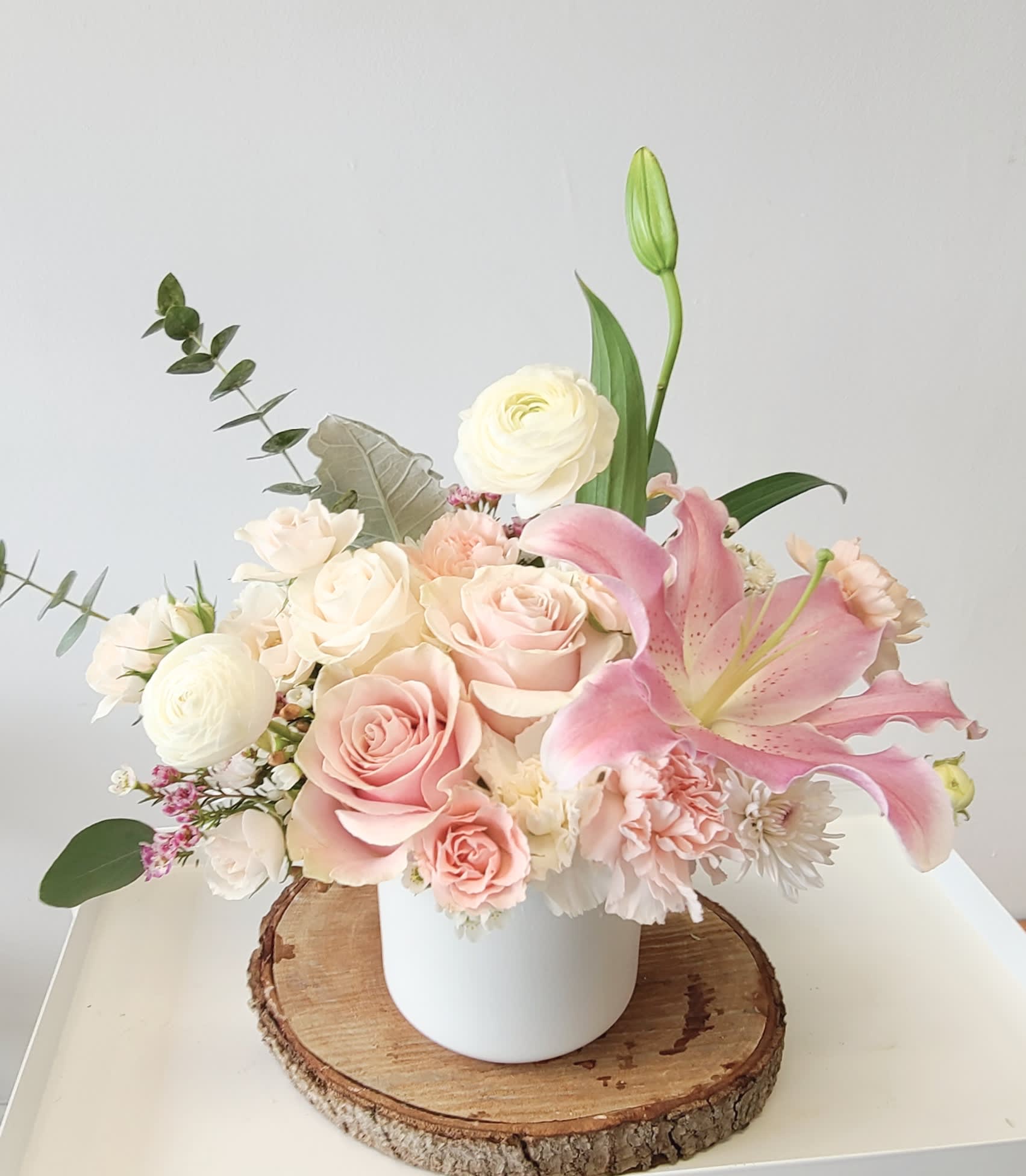 Pink and white floral arrangement in a white vase with a pink lily