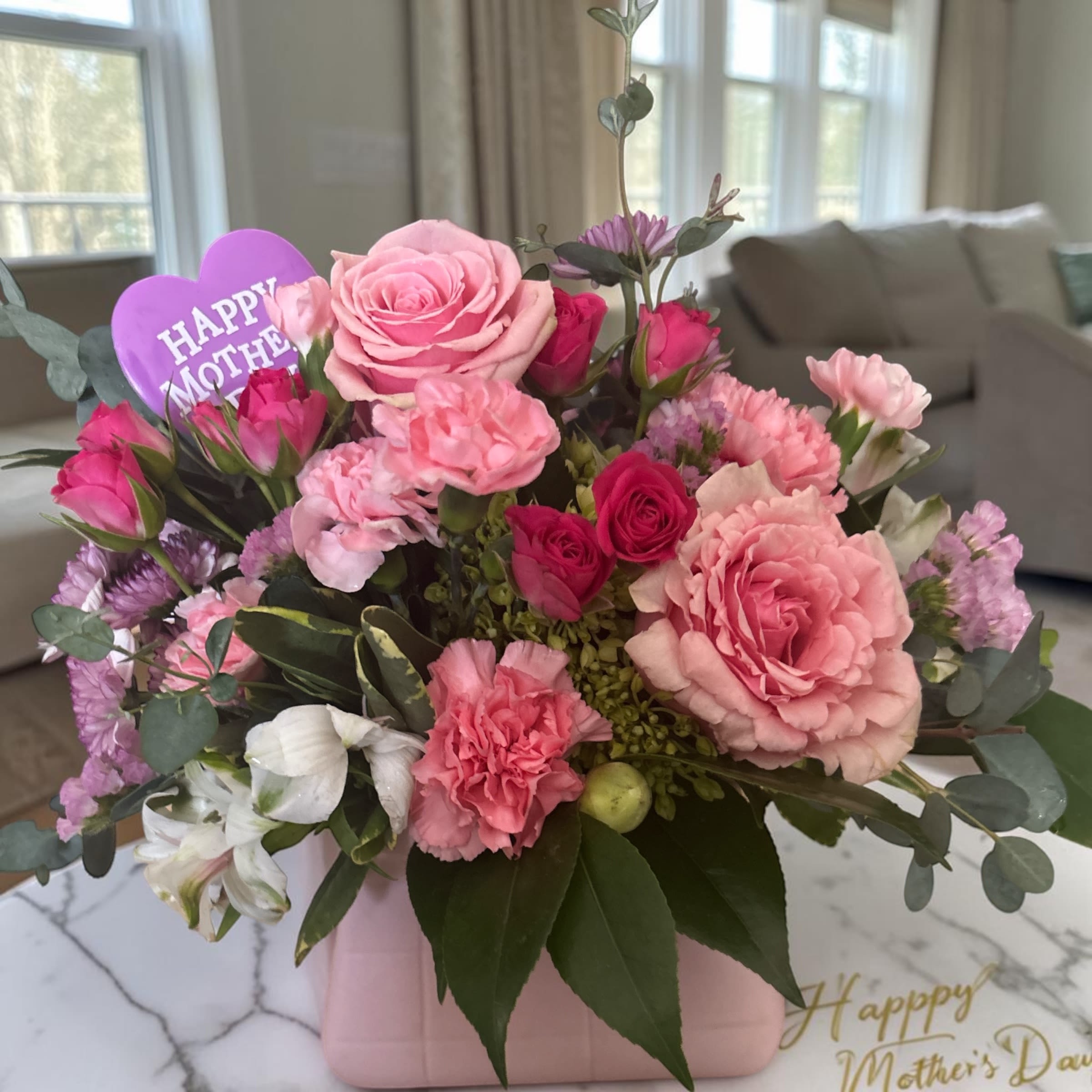 Pretty Pink Purse - Pretty Pink Purse is a stylish Mother’s Day flower arrangement designed in a keepsake pink ceramic purse container and filled with fresh blooms in soft shades of pink, blush, white, and lavender. Featuring roses, spray roses, carnations, alstroemeria, seasonal flowers, and fresh greenery, this design is feminine, cheerful, and full of charm.  Perfect for Mother’s Day, birthdays, get well wishes, or just because, this unique floral gift combines fresh flowers with a reusable keepsake container Mom can enjoy long after the blooms are gone.  Handcrafted fresh by Aspen Tower Florist in Greensburg, Indiana, each arrangement is made to order using premium seasonal flowers. Flower varieties may vary while maintaining the same color palette and overall style.  Available for local flower delivery in Greensburg, Indiana and surrounding areas. Order early, as quantities are limited for this specialty keepsake design.