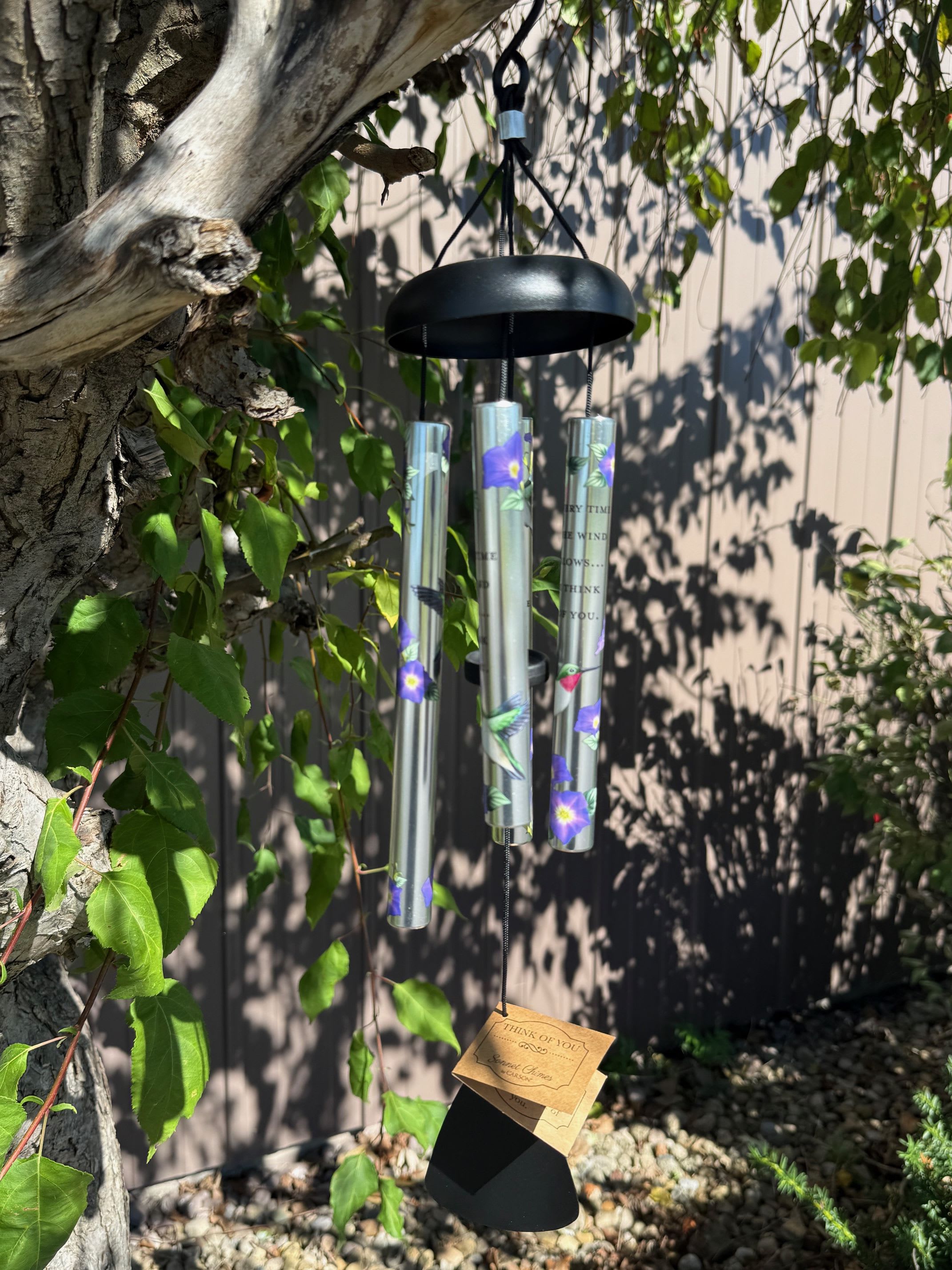 Hanging black wind chime with floral tubes and a tag
