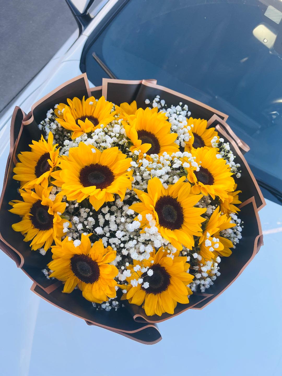 Bouquet of yellow sunflowers with white baby's breath in black wrap
