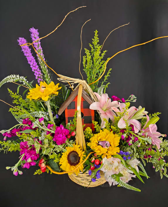 Basket arrangement with sunflowers, pink lilies, and purple flowers