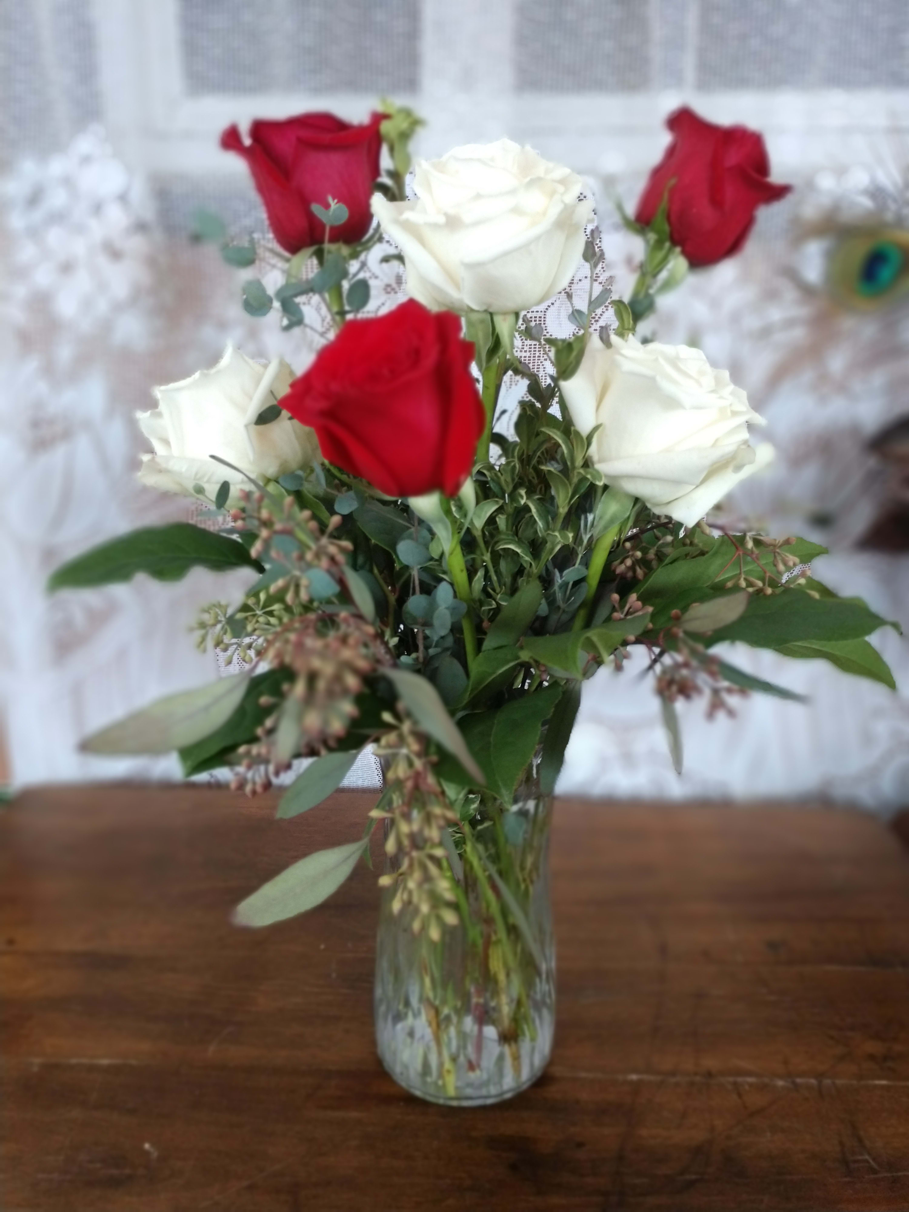 Red and white roses arranged in a clear glass vase