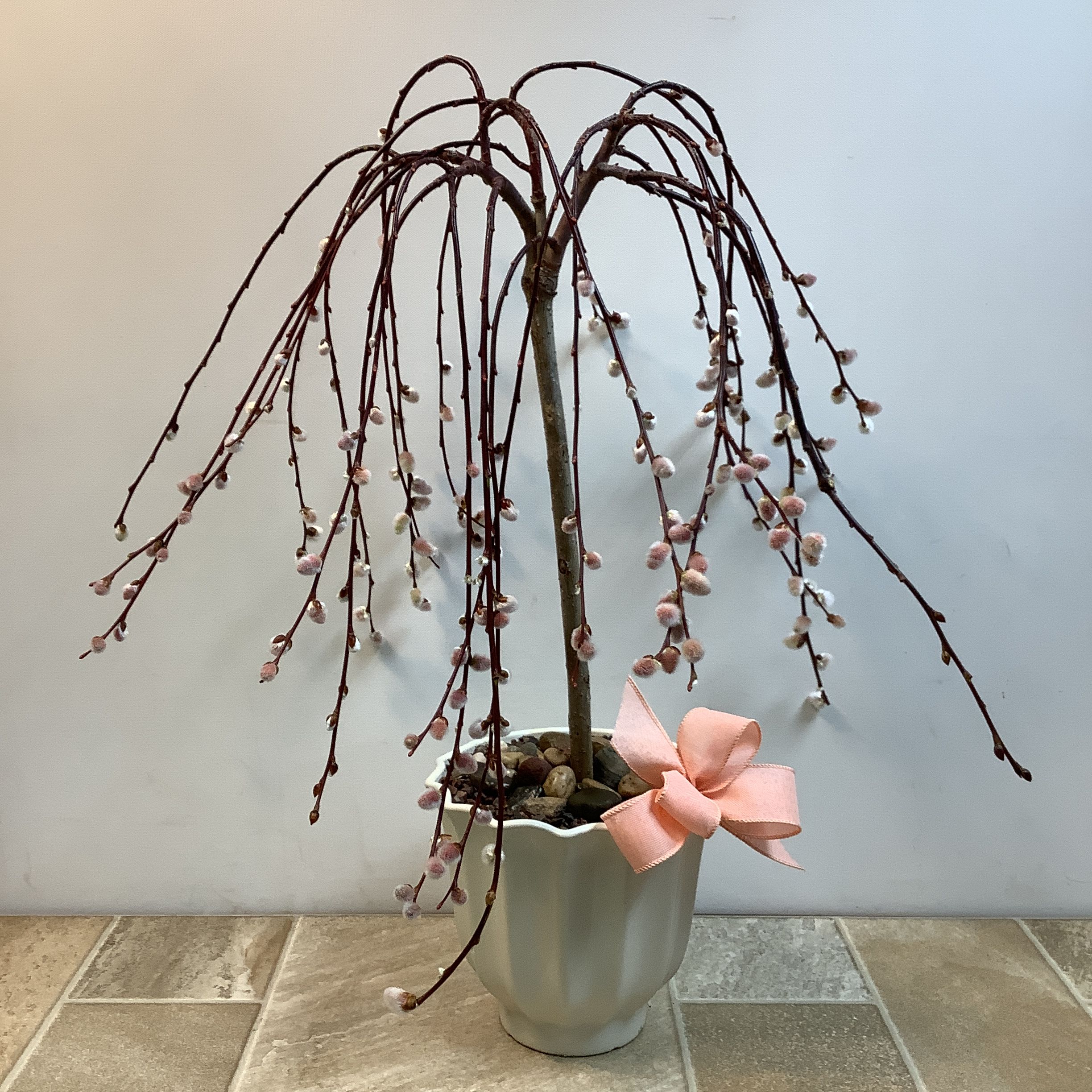 Potted flowering branch arrangement with a pink ribbon