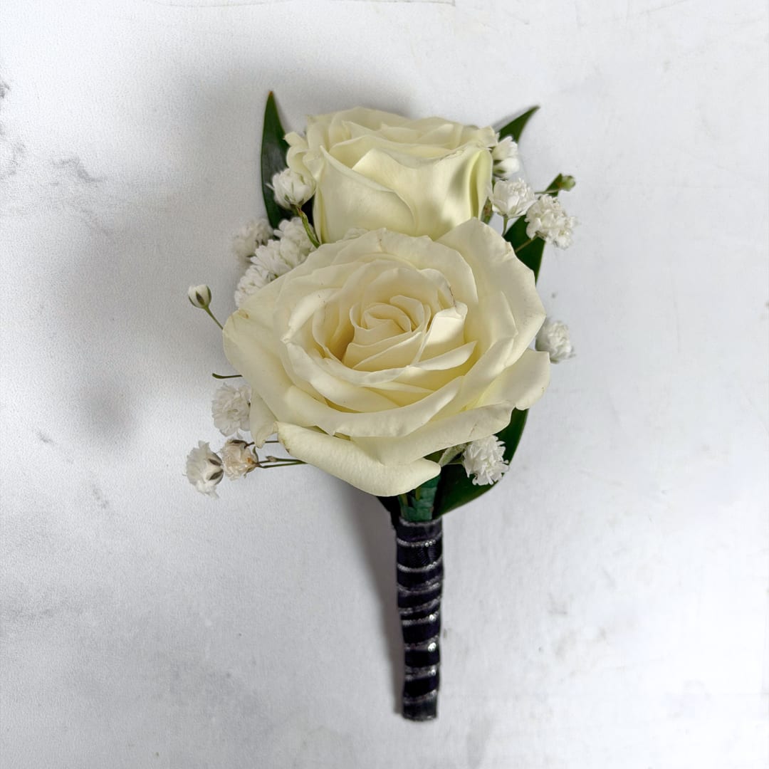 Onyx Boutonniere - With Wrap - Two ivory-white roses create the refined focal point of Onyx Boutonniere, a classic boutonniere perfect for prom night. Small white baby's breath filler and deep green leaves tuck around the roses for a soft, elegant contrast while the shimmering black and silver ribbon wrap adds a subtle flair to elevate the boutonniere to the next level.  The black and white color palette of this boutonniere reads timeless and understated; these colors work extremely well with most dress and suit colors, allowing for lots of creative freedom. The boutonniere comes with a pin to keep it nice and secure on lapels during through photos and dancing, so the wearer will feel effortlessly put together for prom while having a great time on the dance floor.  If you want to change the color of the ribbon wrap, or want to add on a bit of sparkle for a dazzling accent, check out our add-ons below or at checkout to choose your preferred color.