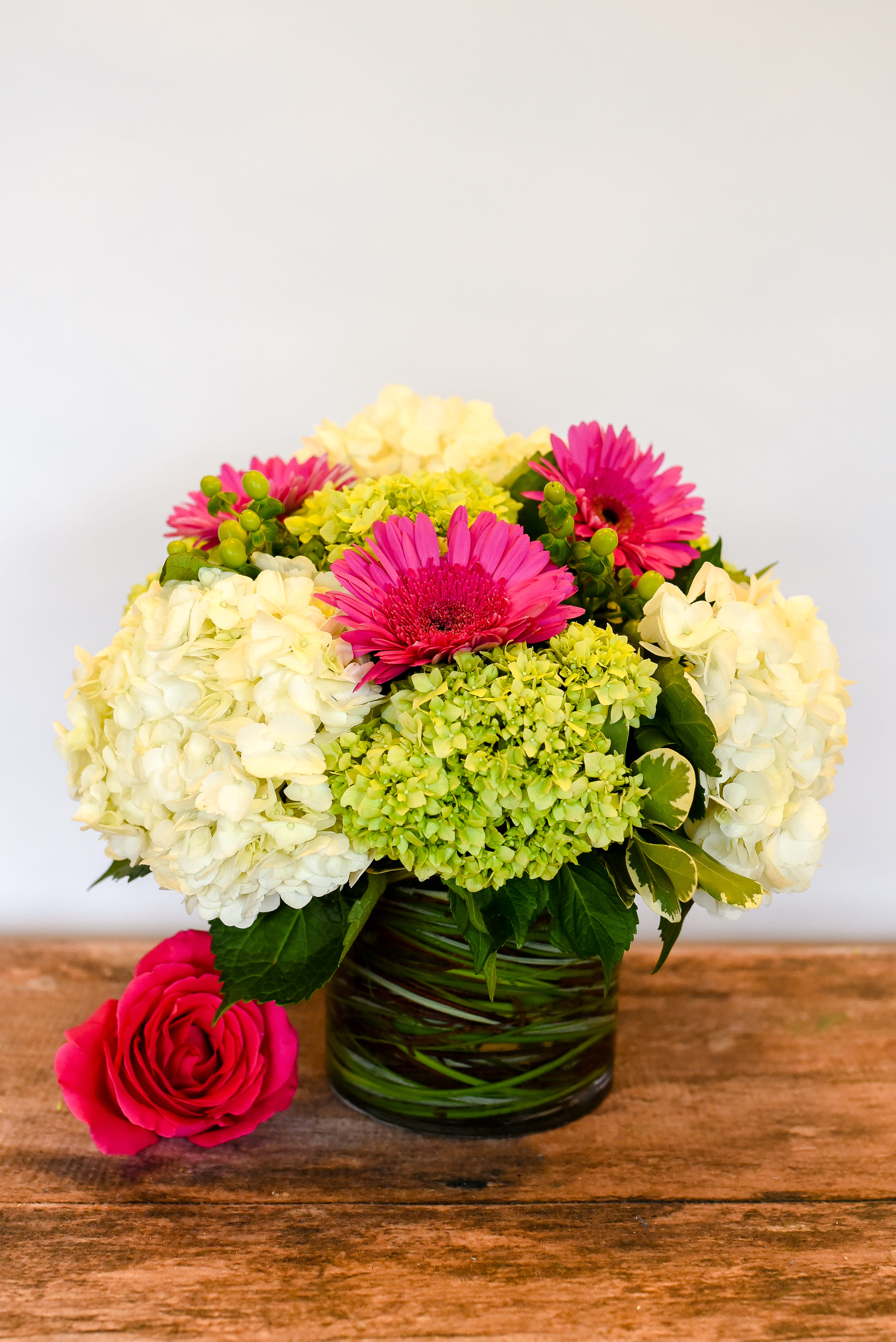 Pink gerbera daisies and white hydrangeas in a glass vase