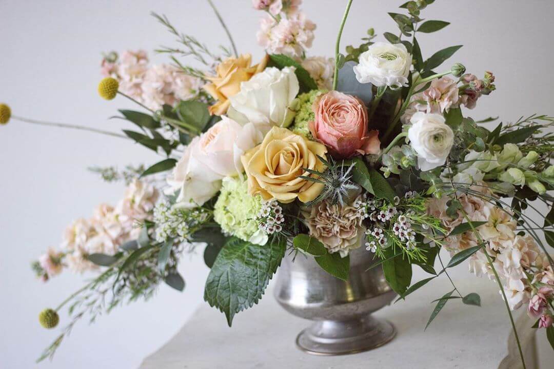 Mixed bouquet of roses and ranunculus in a silver vase