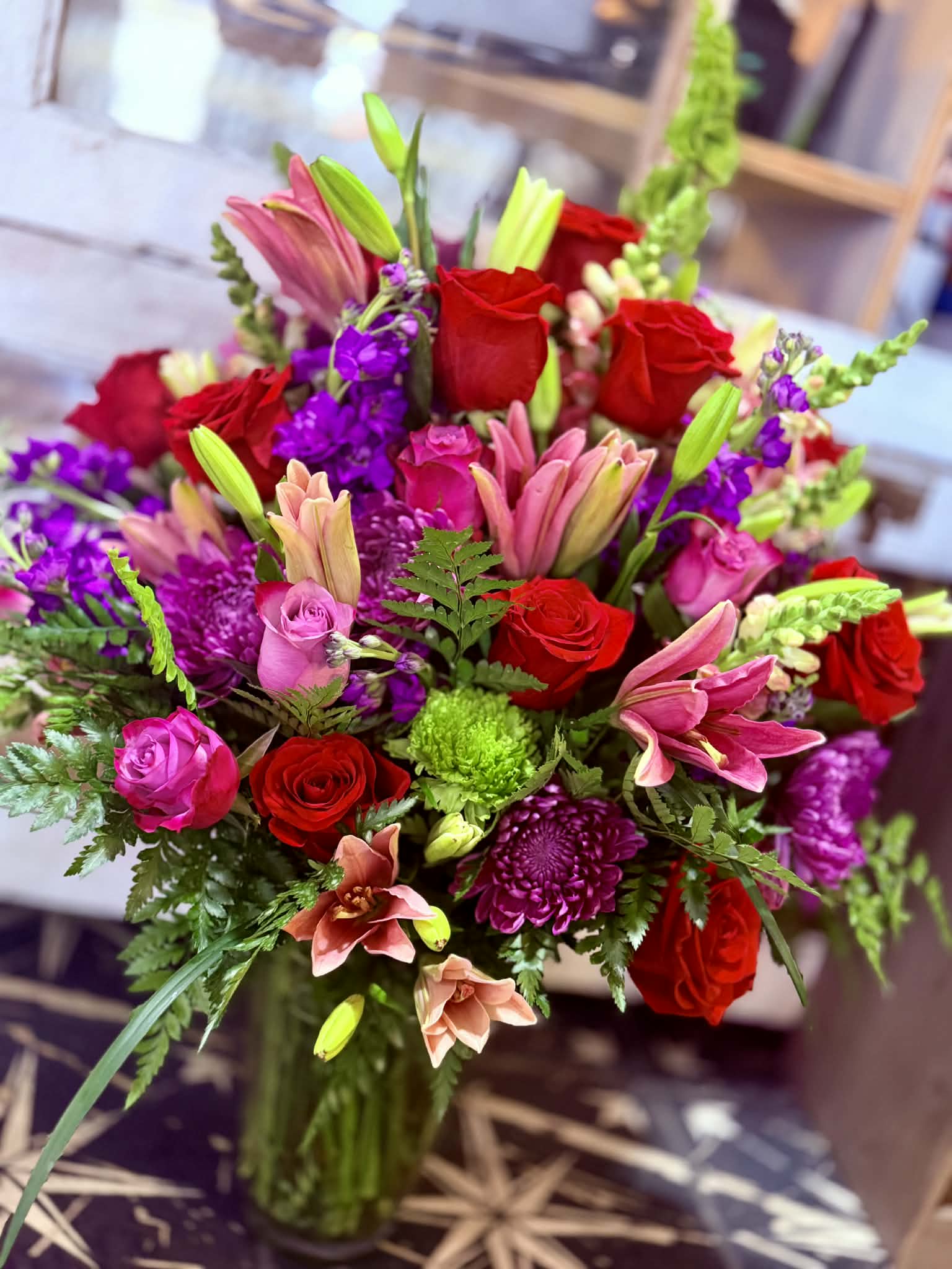 Bouquet of red roses, pink lilies, and purple flowers in a vase