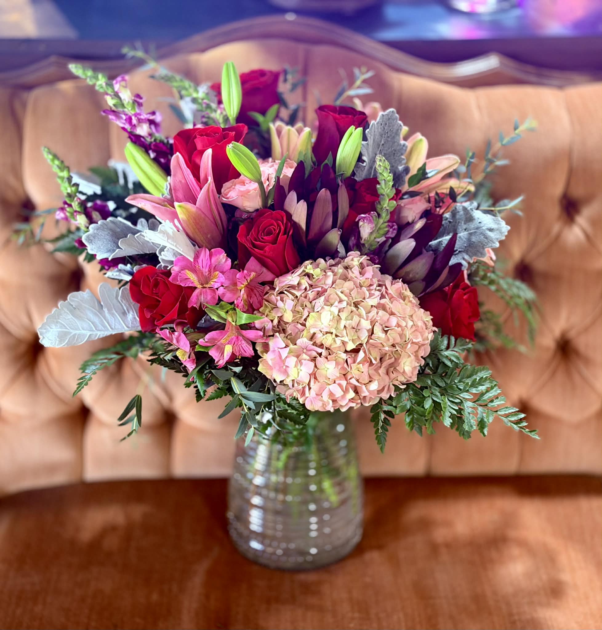 Bouquet of red roses, pink lilies, and hydrangea in a glass vase