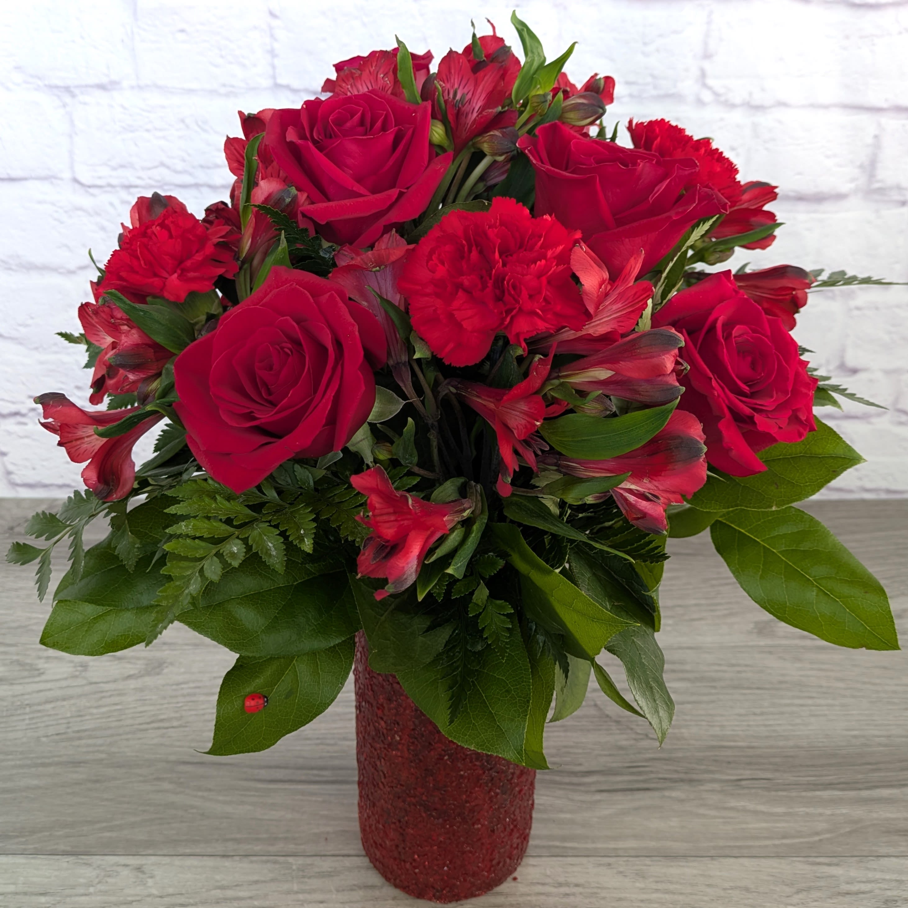 Hearts and Kisses - Hearts and Kisses is A Ladybug Floral exclusive bouquet. This bouquet includes roses, carnations, and alstroemeria. Featured in a 9” glass cylinder with a crushed shimmer finish.  Orientation: All Around 18” Tall 14” Wide  