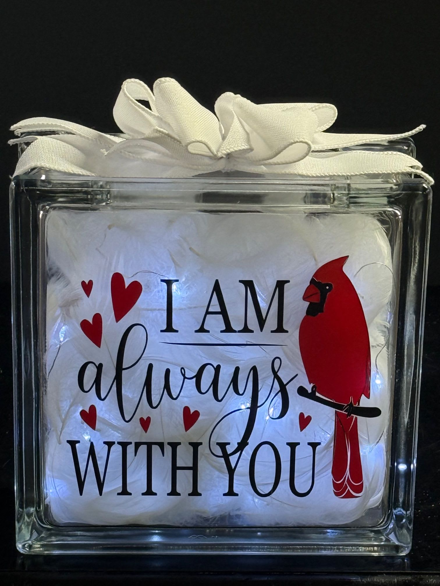 Clear gift box with white feathers and a red cardinal graphic reading "I AM always WITH YOU"