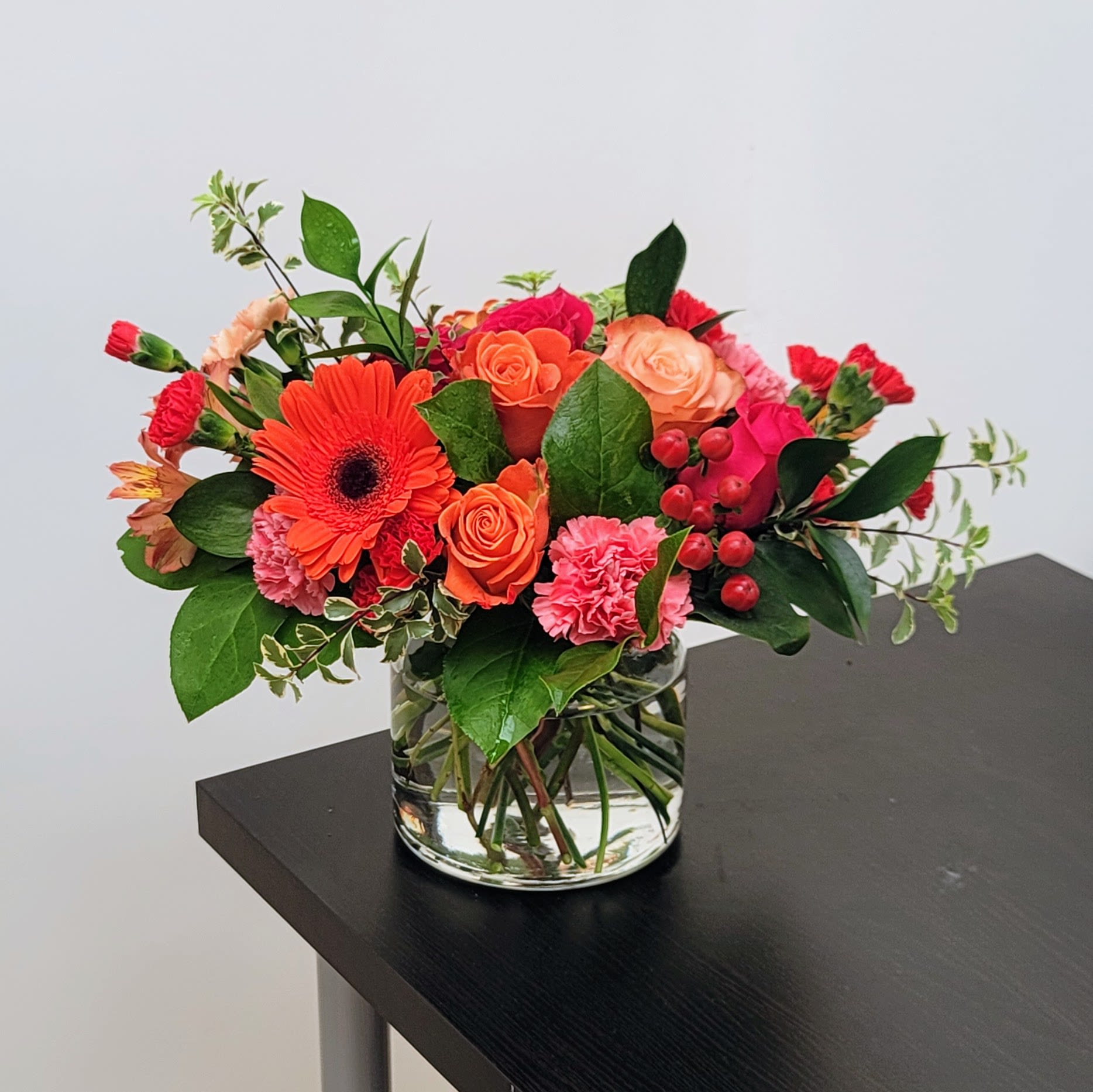 Fiesta Bouquet - Brighten any moment with this vibrant mix of pink and orange roses, red gerberas, and seasonal bright and festive floral accents. Handcrafted by our talented florists, this cheerful arrangement arrives ready to dazzle.  Perfect for birthdays, anniversaries, or just because! Send this beauty today! Approximately 14"H x 13" W. 