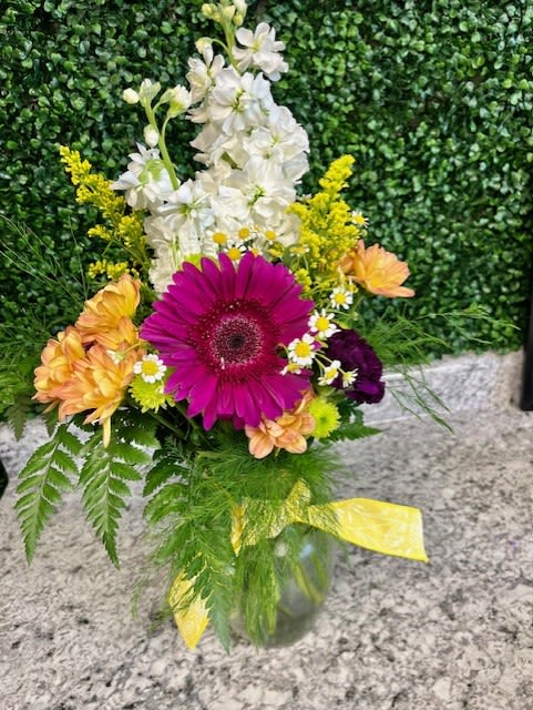 Mixed bouquet with a magenta gerbera daisy and white flowers in a glass vase
