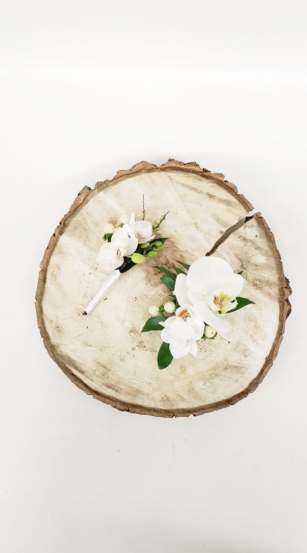 White orchid corsages on a wood slice background