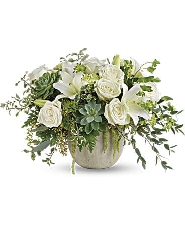 White roses and lilies arranged in a low ceramic vase with succulents